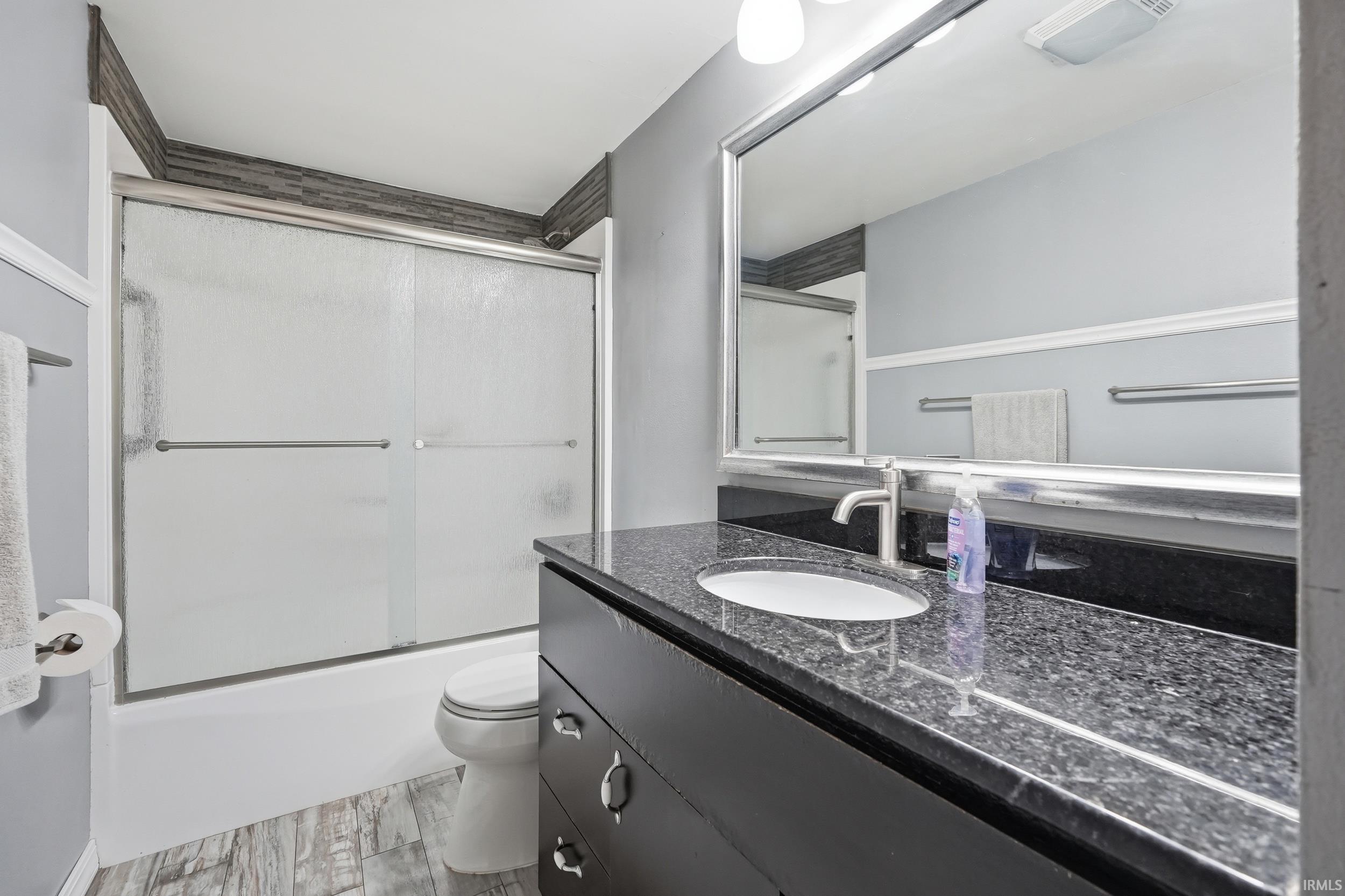 Bathroom featuring a dark wood-finish vanity with a granite countertop and an undermount sink
