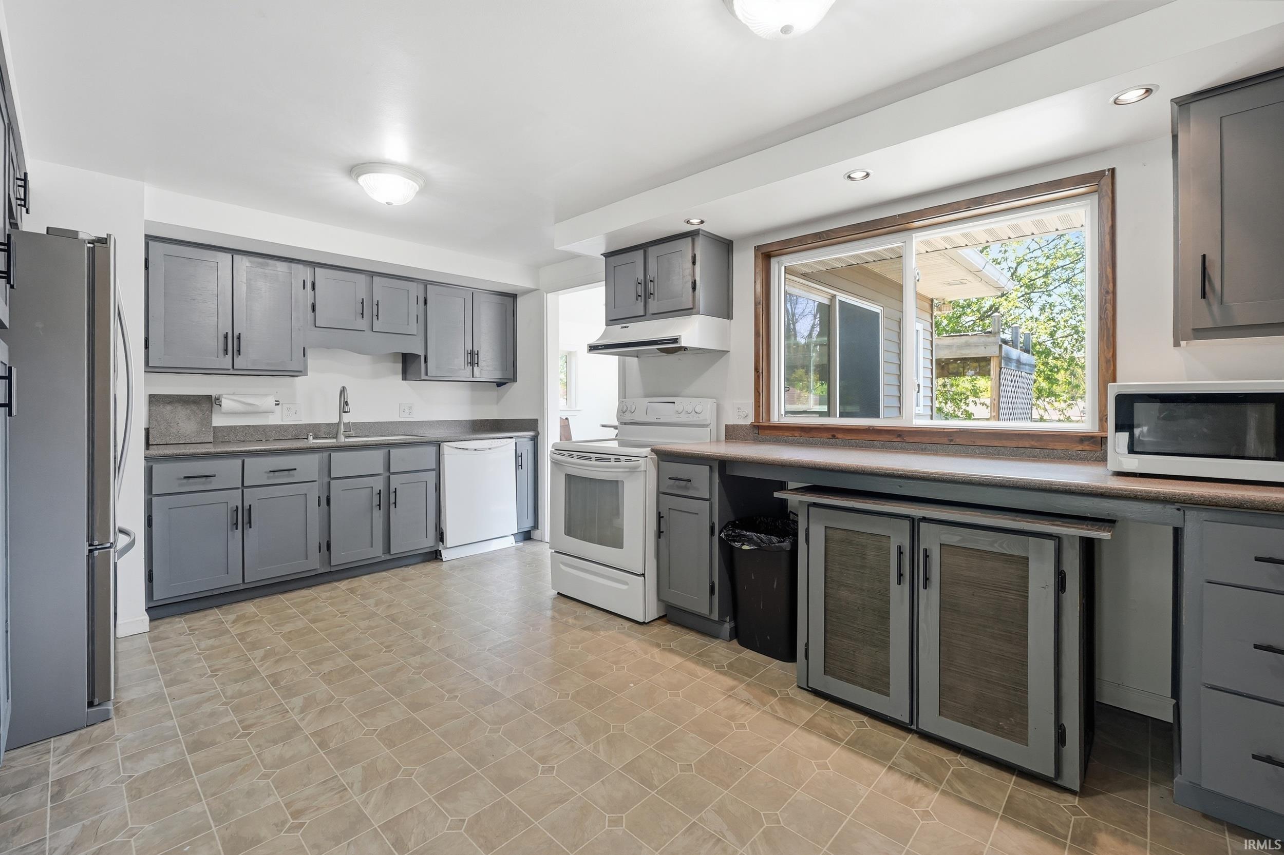 Kitchen with gray cabinetry, a deep sink, and a white dishwasher