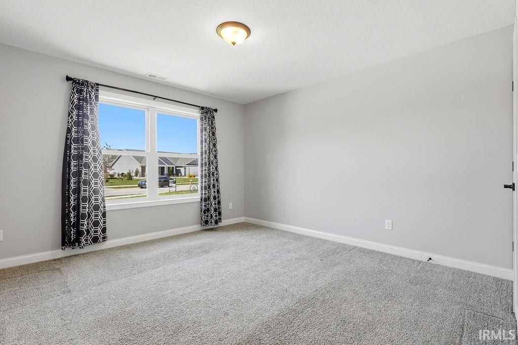 Spacious room featuring a double window, light gray wall paint, white trim, and light gray carpet