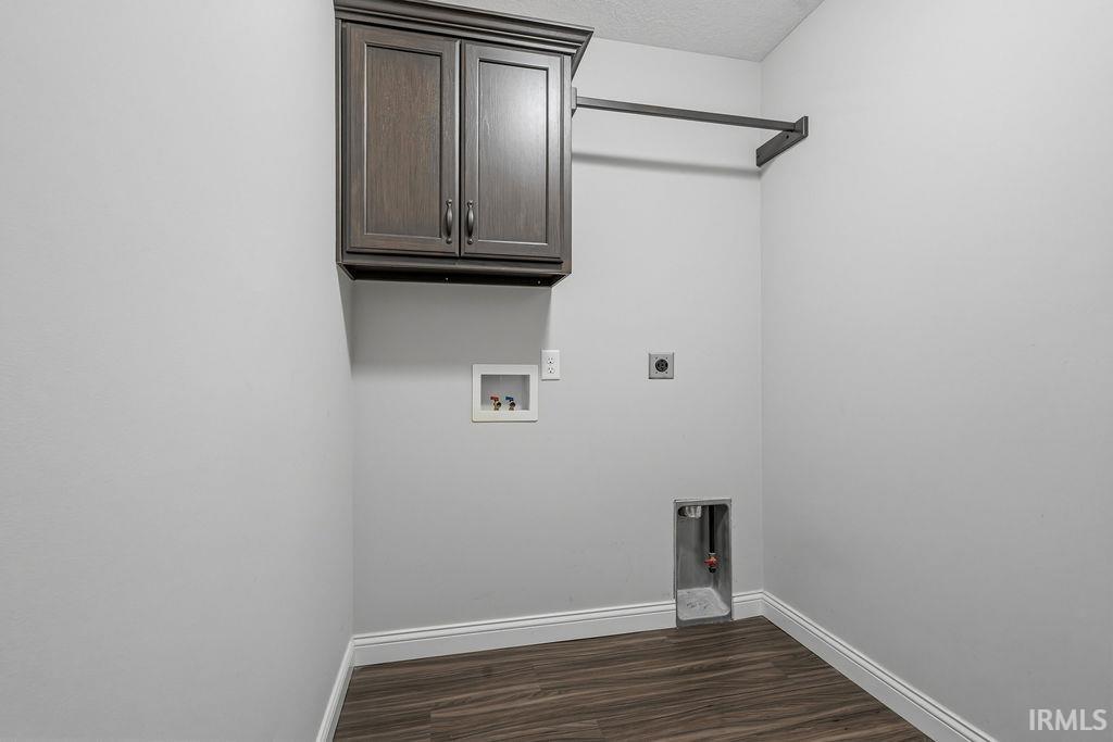 Laundry area featuring wood-finish flooring, light gray walls, built-in dark wood cabinetry, and a wall-mounted hanging rod