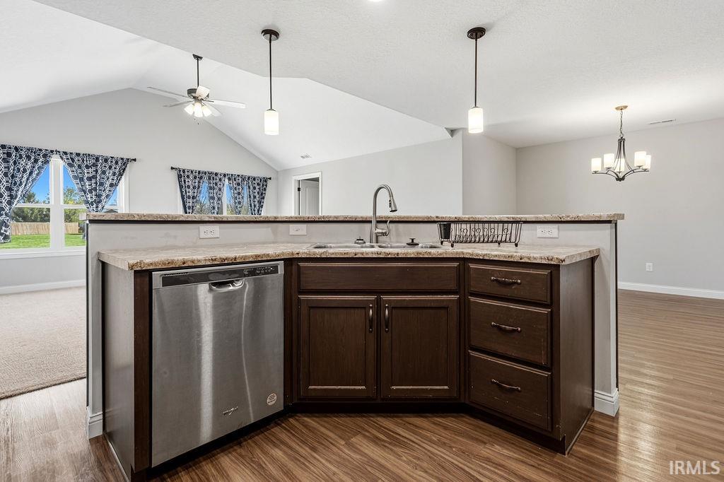 Kitchen island featuring a stainless steel dishwasher, a sink with a gooseneck faucet, and ample cabinetry