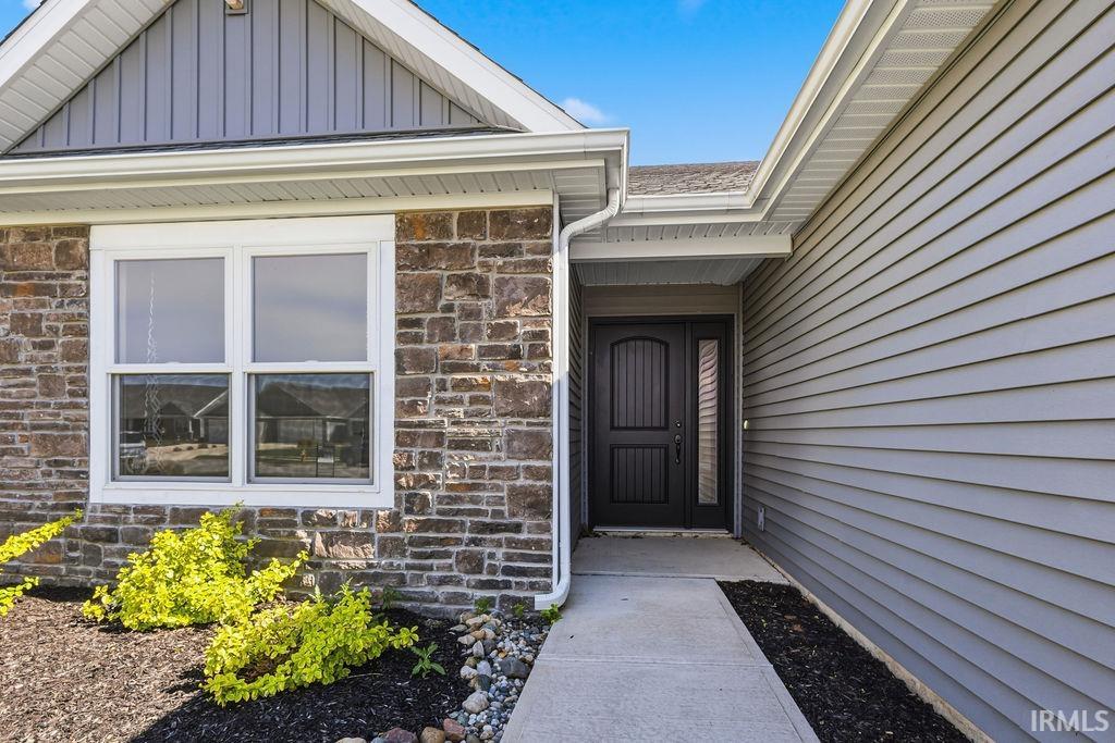 Stone and siding exterior with a dark wood-finish entry door and sidelight