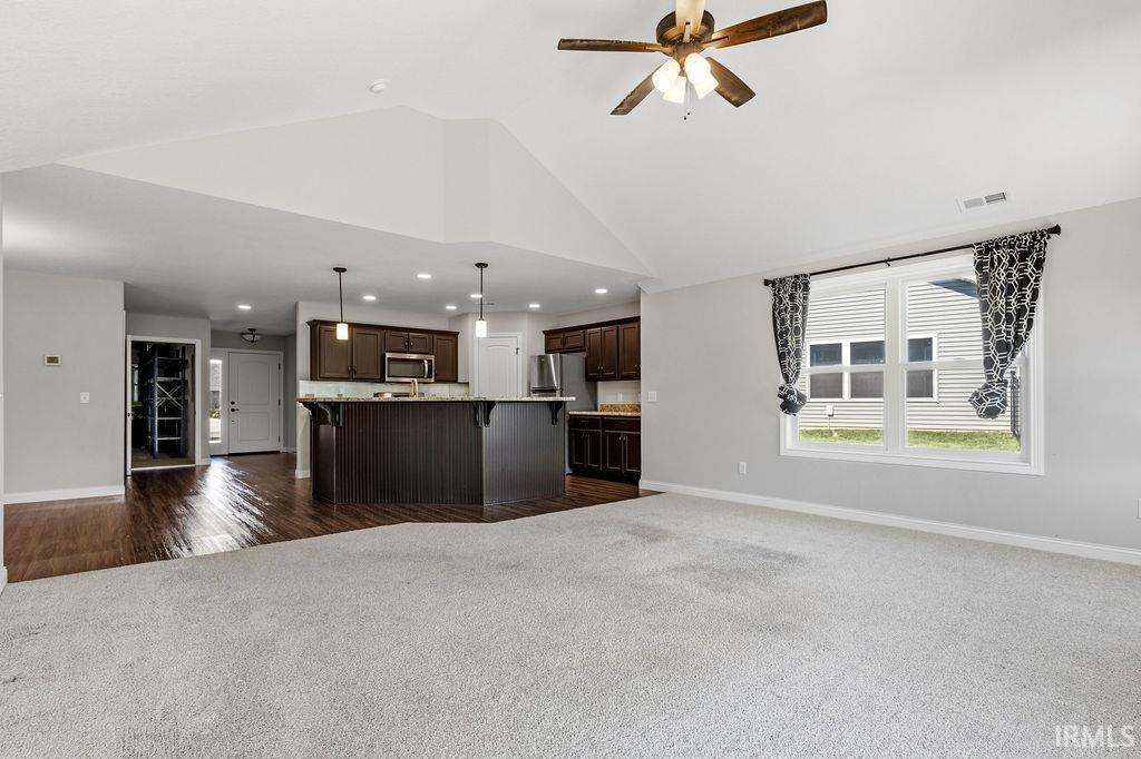 Spacious open-concept interior featuring light gray wall tones and vaulted ceilings