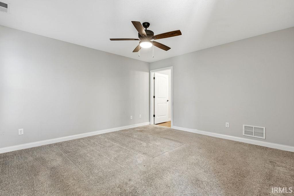 Carpeted room with light grey walls, white baseboards, and a dark wood-finish ceiling fan