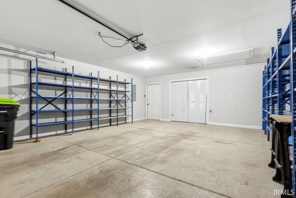 Spacious garage featuring a concrete floor, bright overhead lighting, and built-in industrial shelving