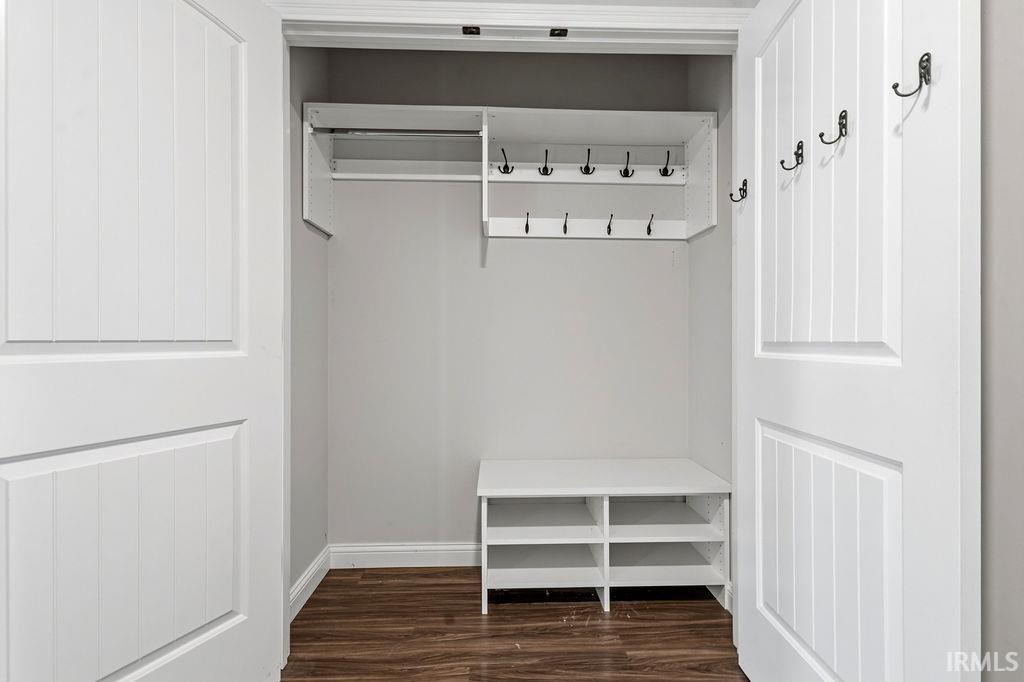 Recessed closet featuring panel doors, a built-in shoe bench, integrated shelving, a clothing rod, and multiple wall-mounted hooks
