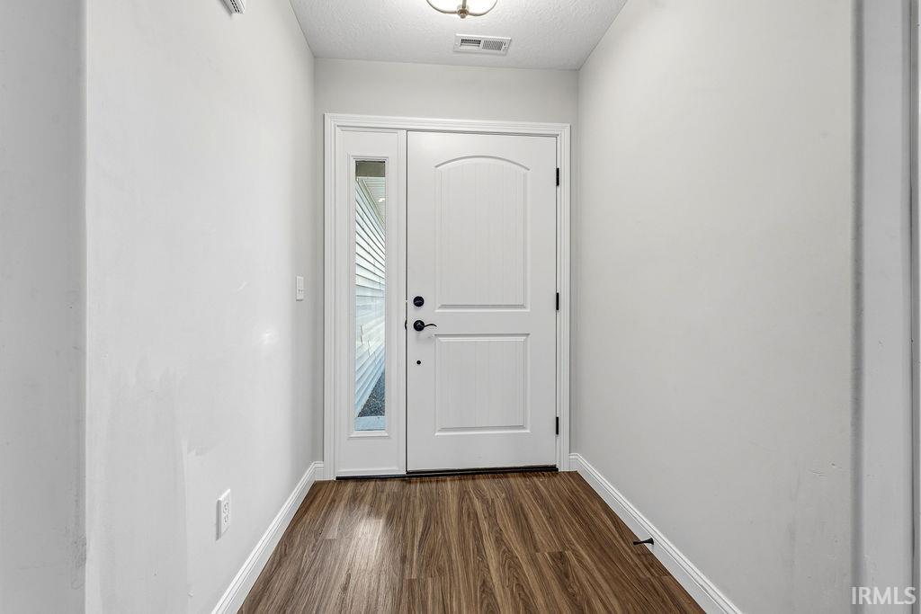 Entryway featuring a paneled door with an arched top detail, adjacent sidelight, and wood-finish flooring