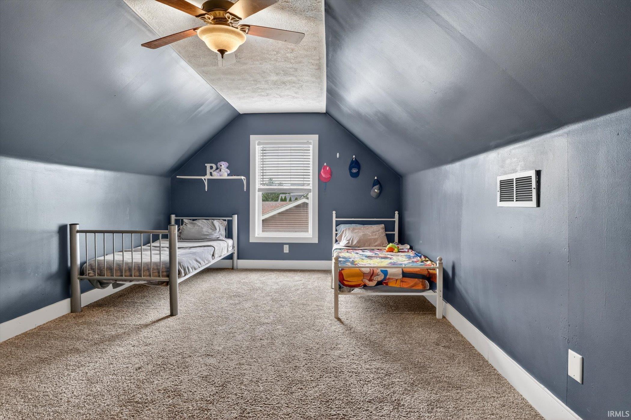 Carpeted room with a ceiling fan, sloped walls, and a window with blinds