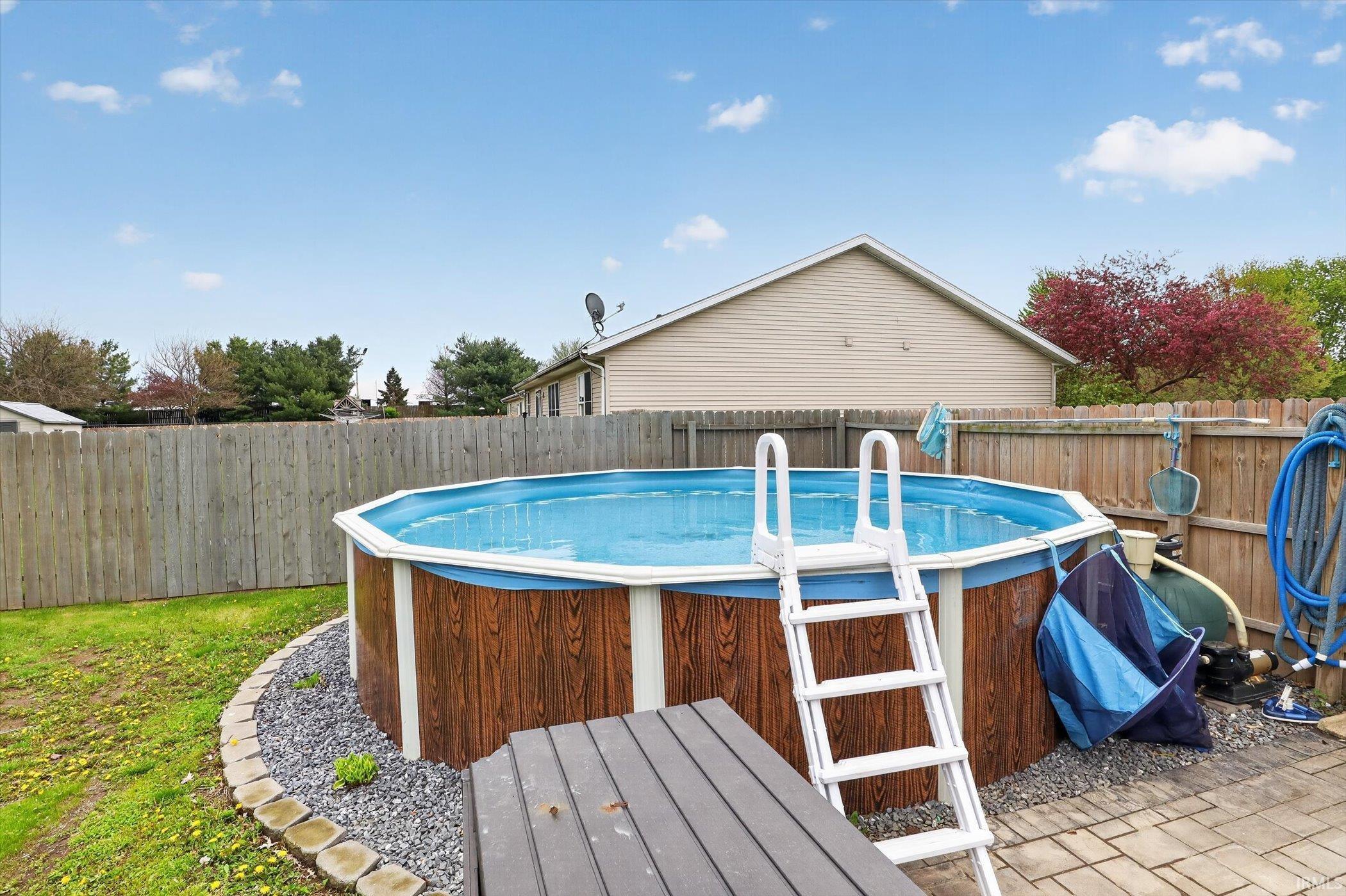 Backyard featuring an above-ground pool with wood-finish siding and a white ladder