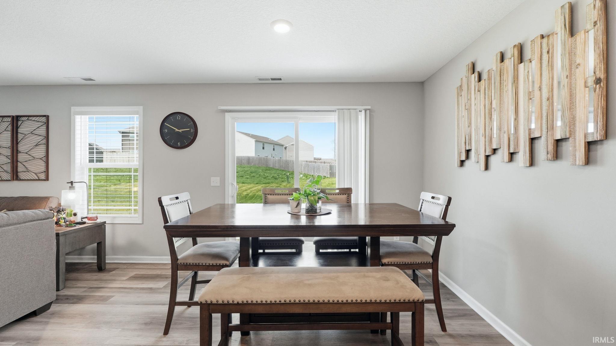 Open-concept dining area featuring wood-finish flooring, a sliding glass door, and two windows
