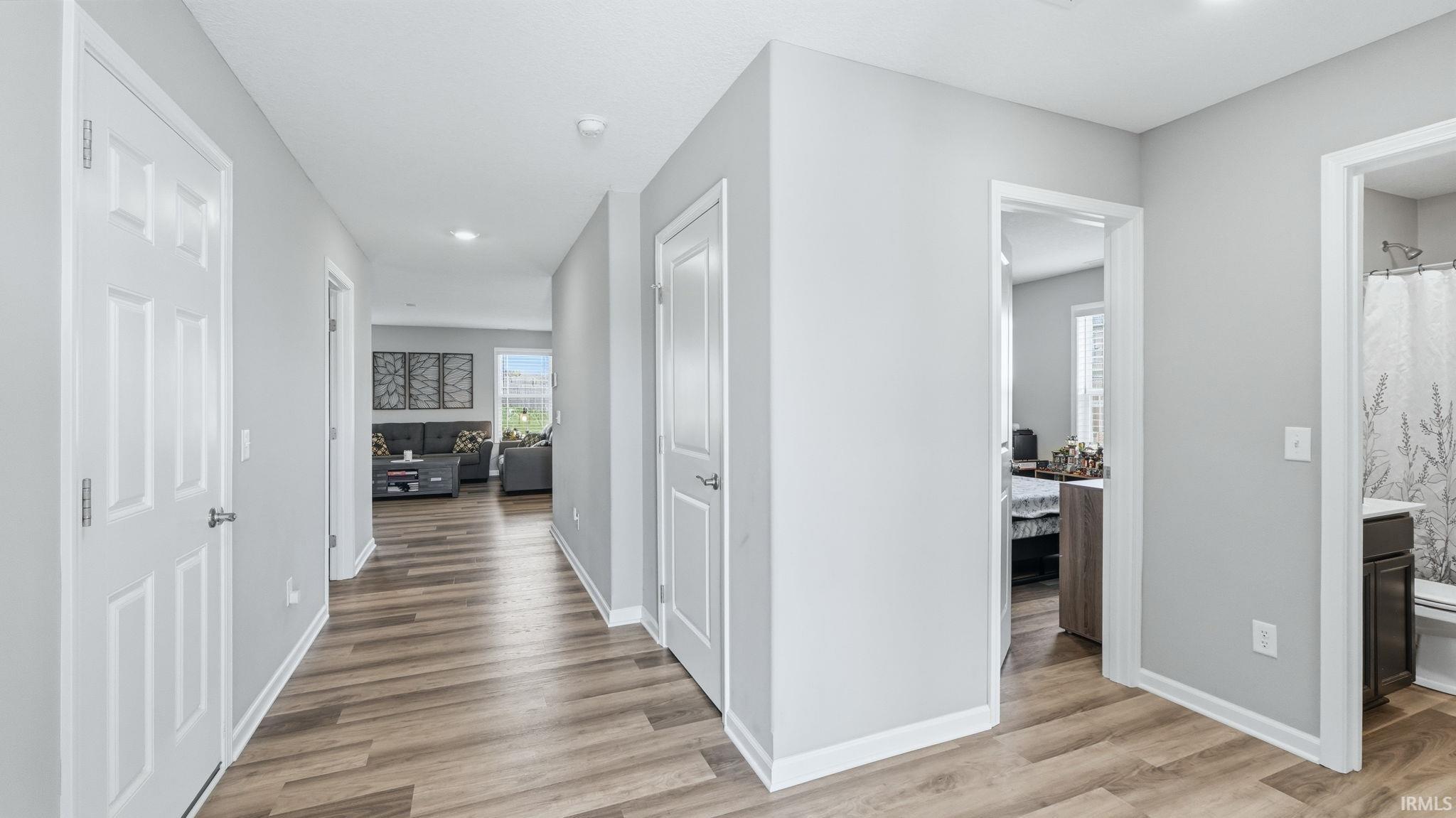 Spacious hallway with wood-finish flooring, light grey walls, and recessed lighting