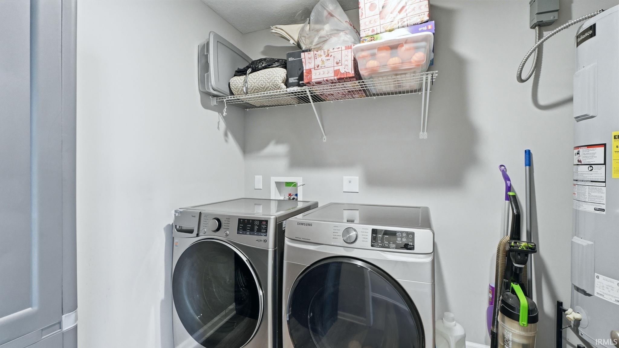 Utility area featuring light gray walls, a built-in wire shelf, a hot water heater, and a bi-fold door