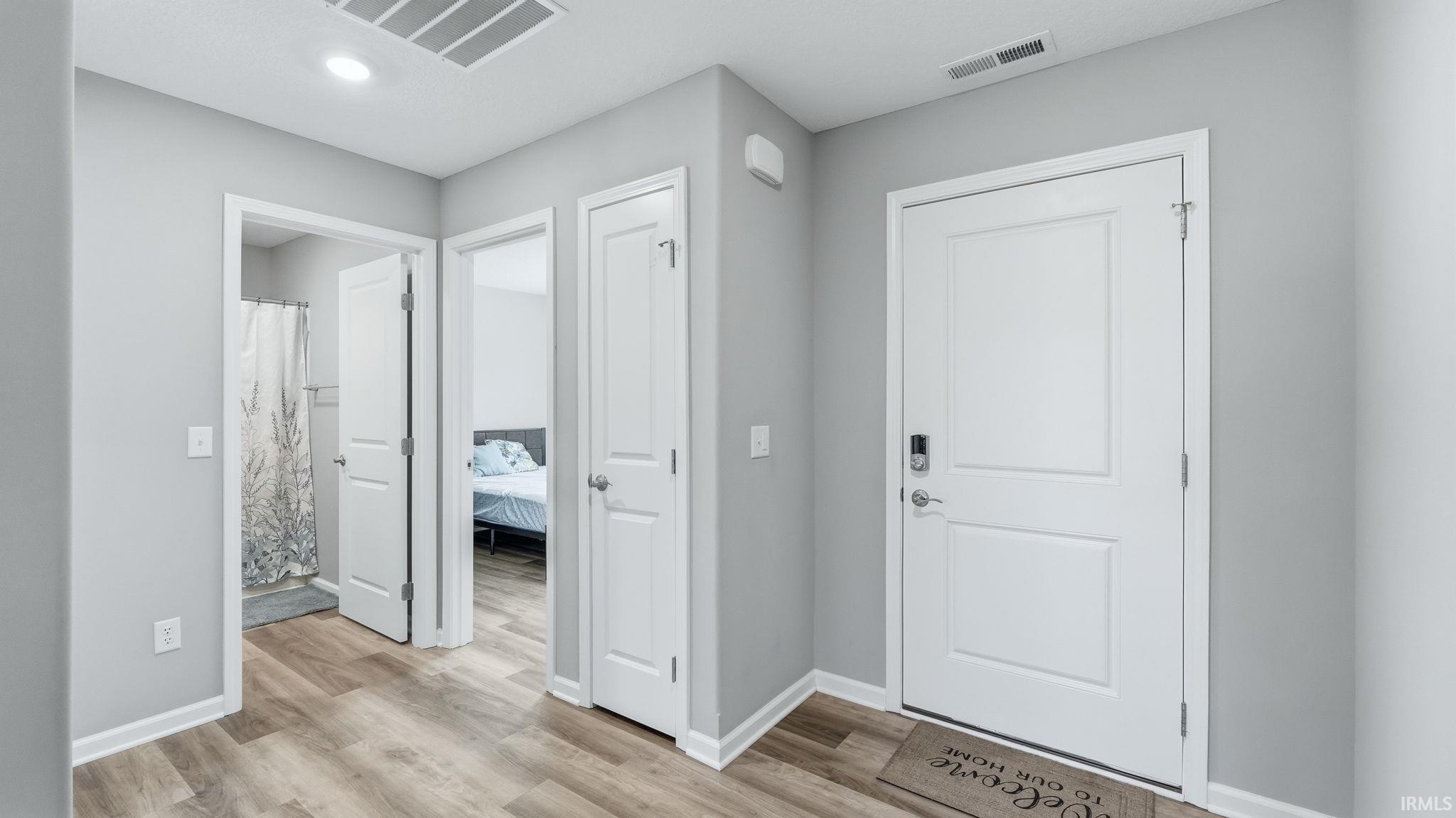 Entryway featuring wood-finish flooring, light gray walls, white trim, and a white paneled door with a smart lock