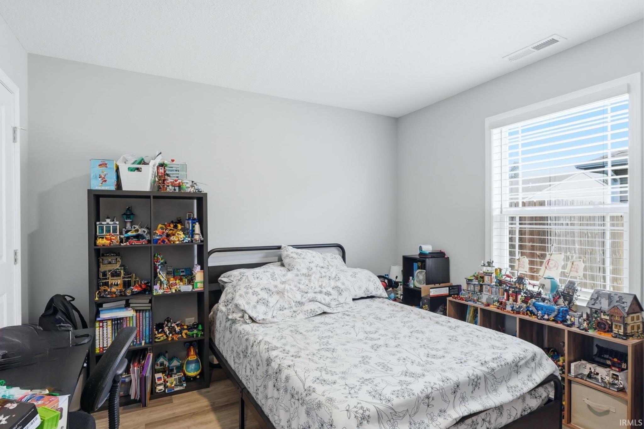 Interior room featuring wood-finish flooring, light gray wall paint, and a white framed window