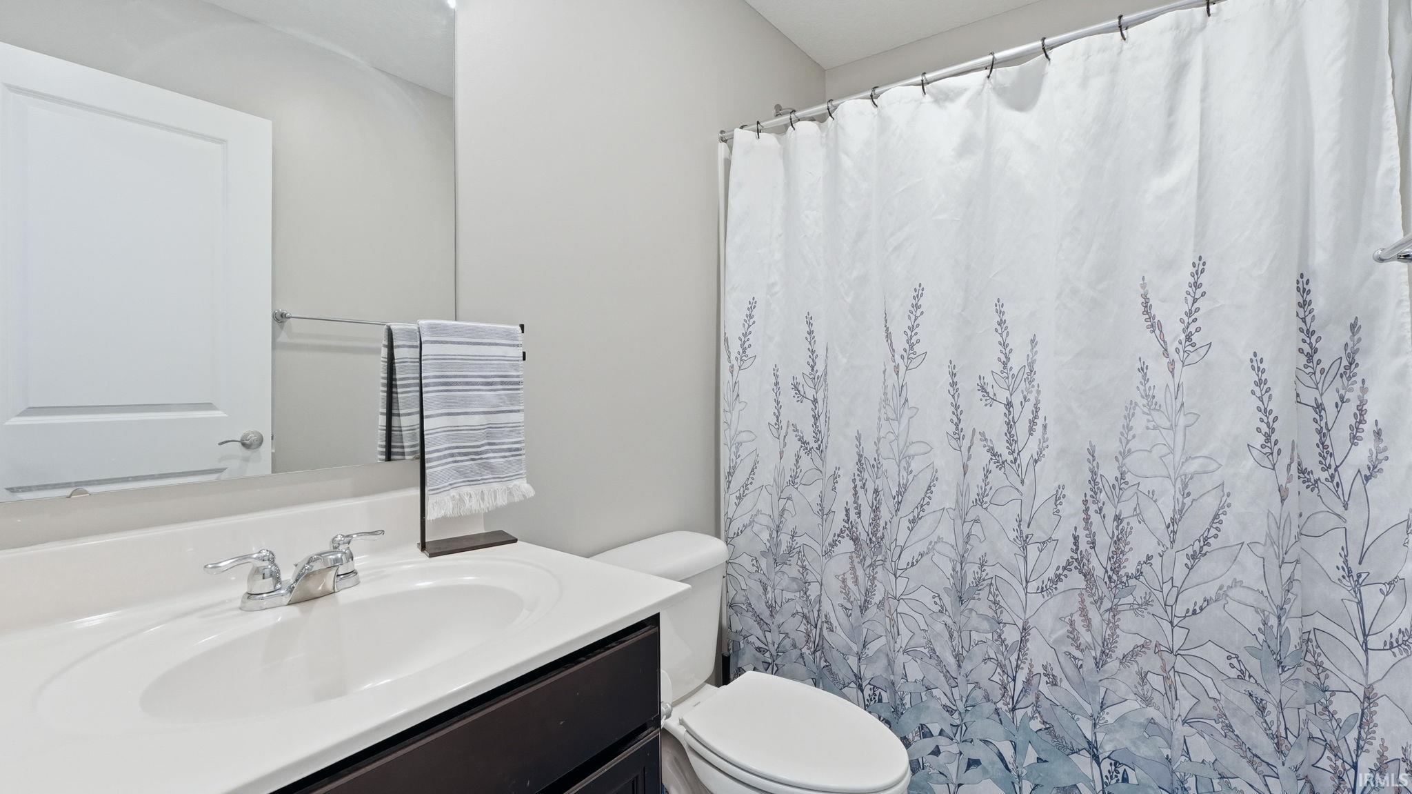 Bathroom featuring a single vanity with an undermount sink, chrome faucet, and a large wall-mounted mirror