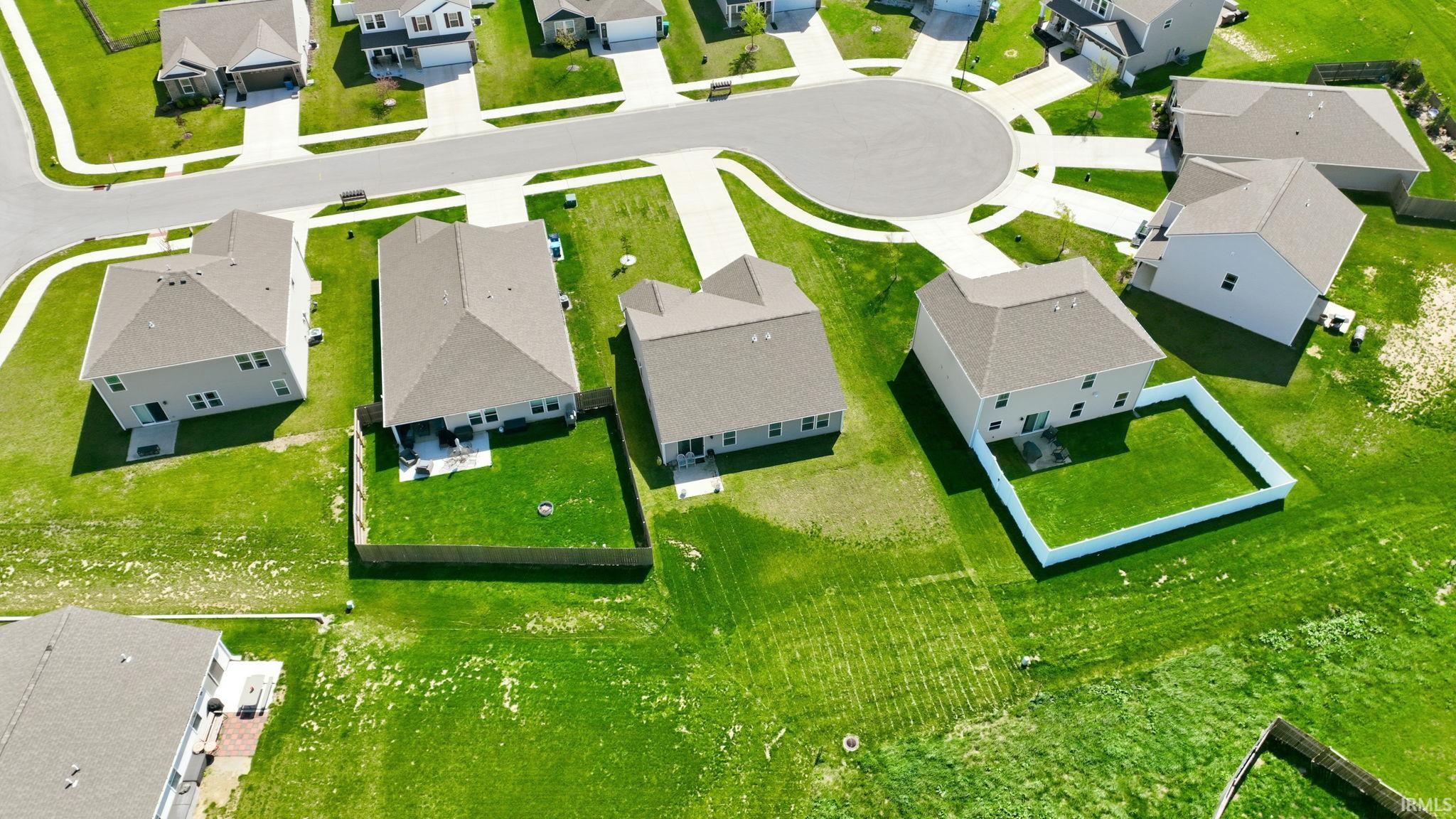 Aerial perspective showcasing a residential development with cul-de-sac design, multiple two-story homes, individual landscaped lawns, and established fencing