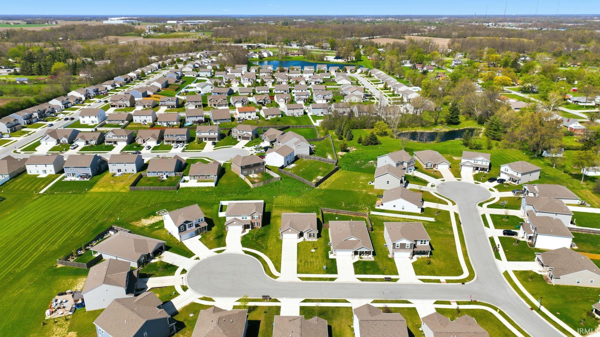Aerial perspective showcasing a residential community with numerous single-family homes, paved streets, and green spaces