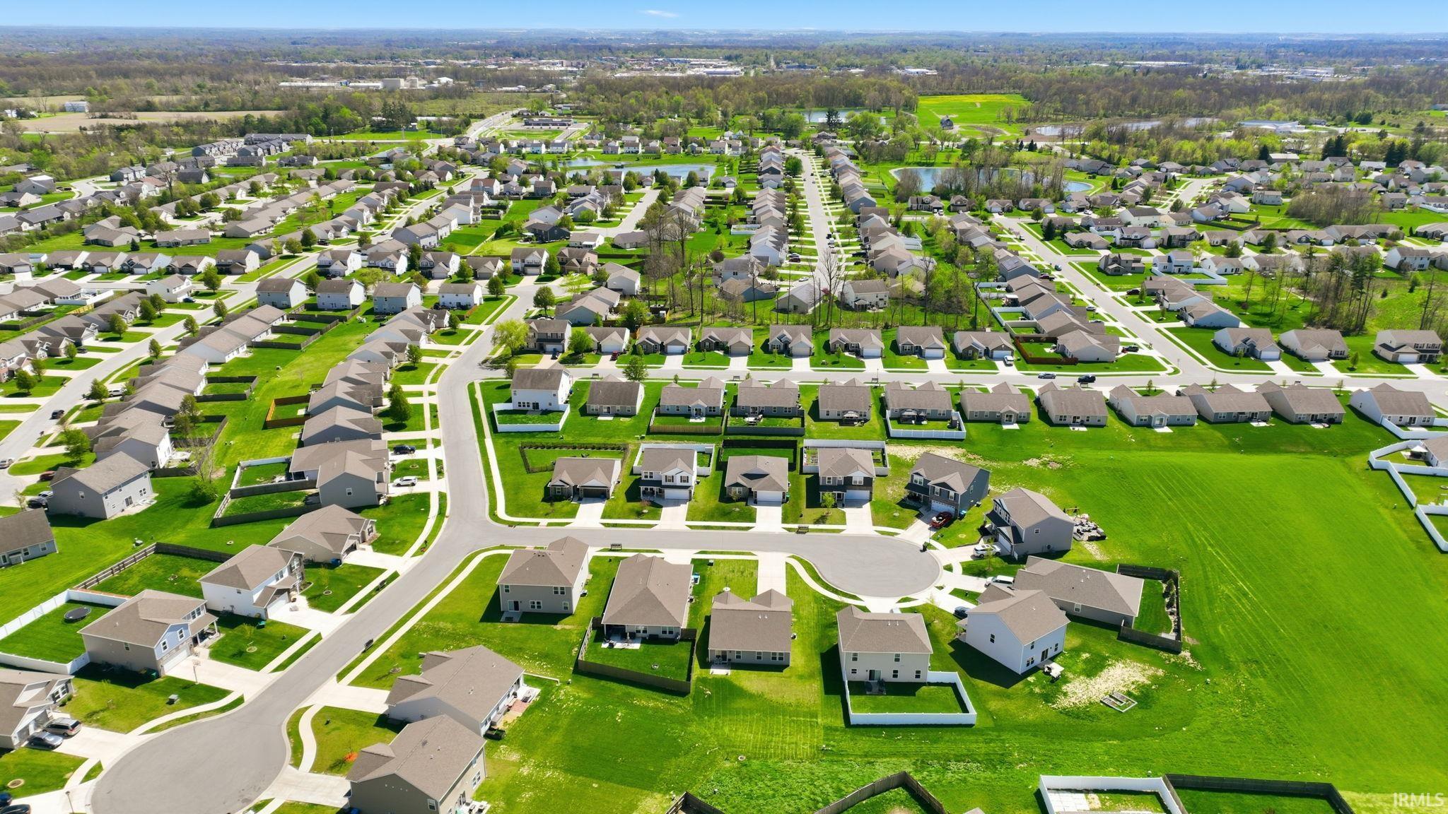 Aerial perspective showcasing a residential development with multiple single-family homes, manicured lawns, and paved streets