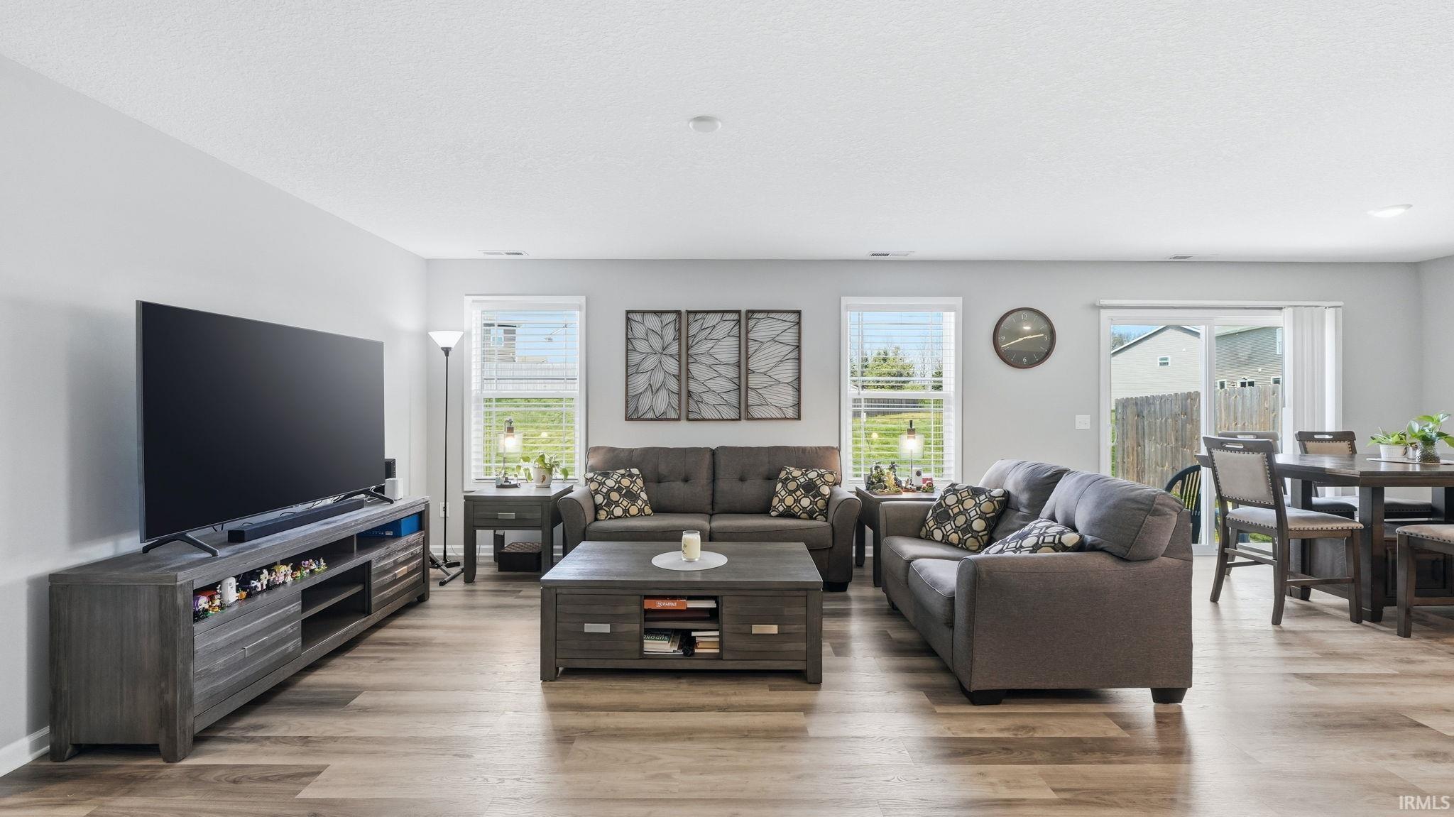 Open-concept living area with wood-finish flooring, light grey wall tones, recessed lighting, and white baseboards