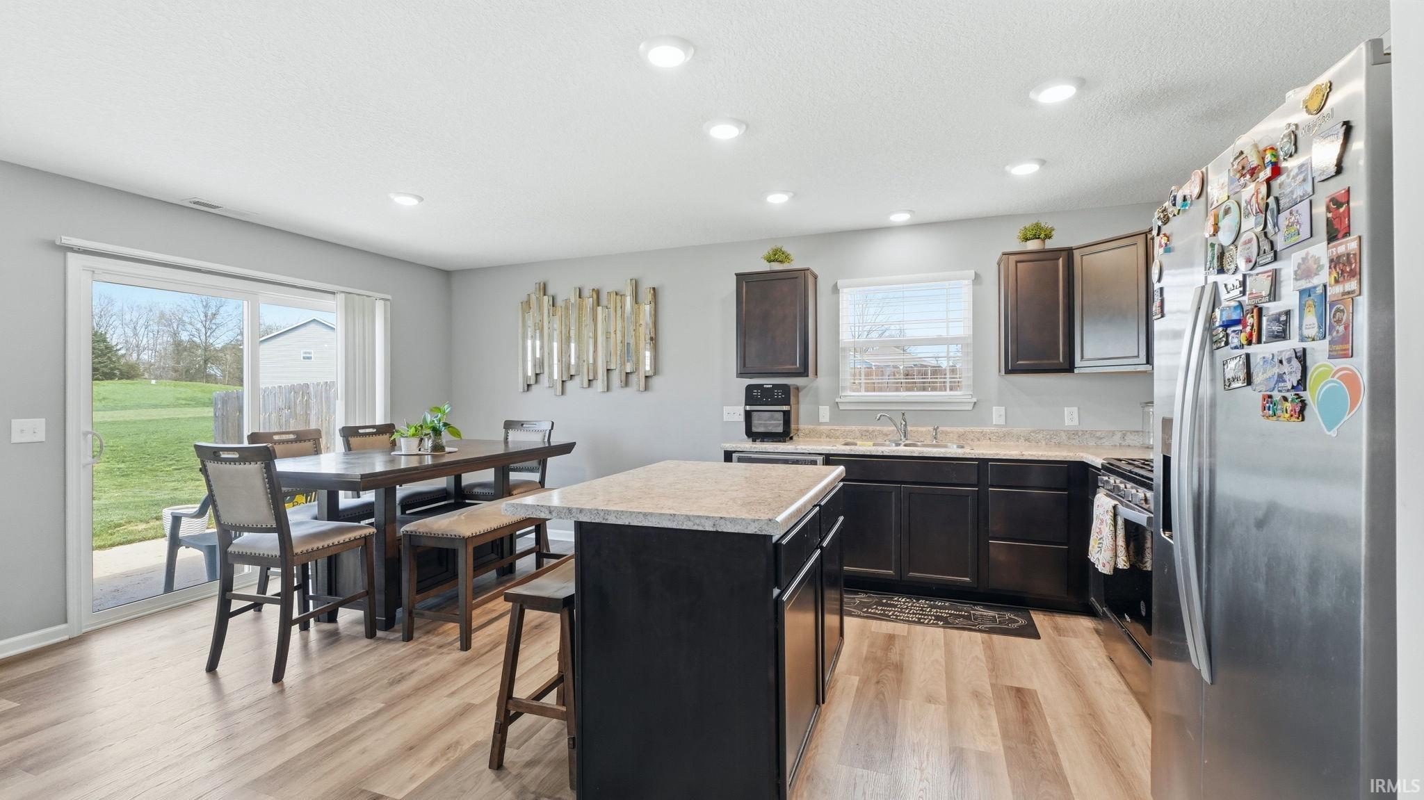 Kitchen featuring dark wood cabinetry, light countertops, and wood-finish flooring