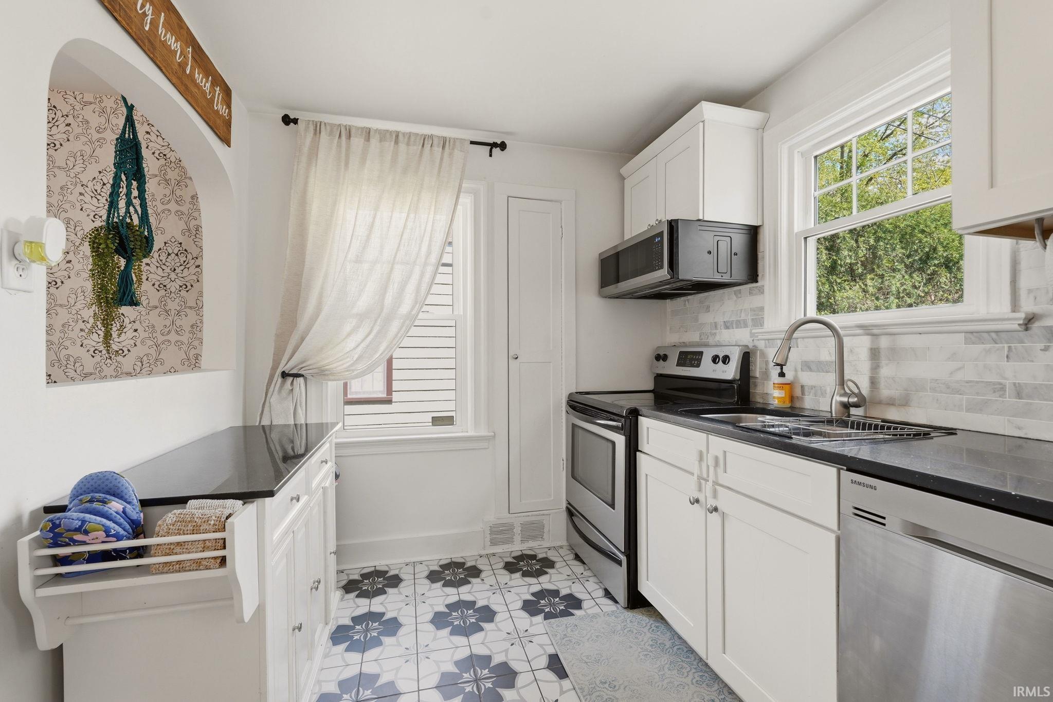 Kitchen featuring white cabinetry, black countertops, and a subway tile backsplash