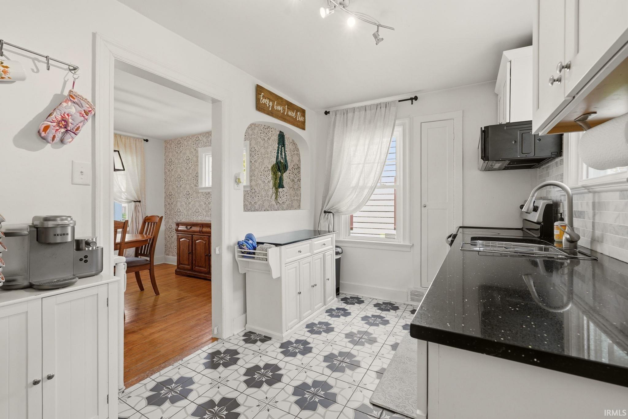 Kitchen featuring patterned floor tiles, white cabinetry, and dark countertops