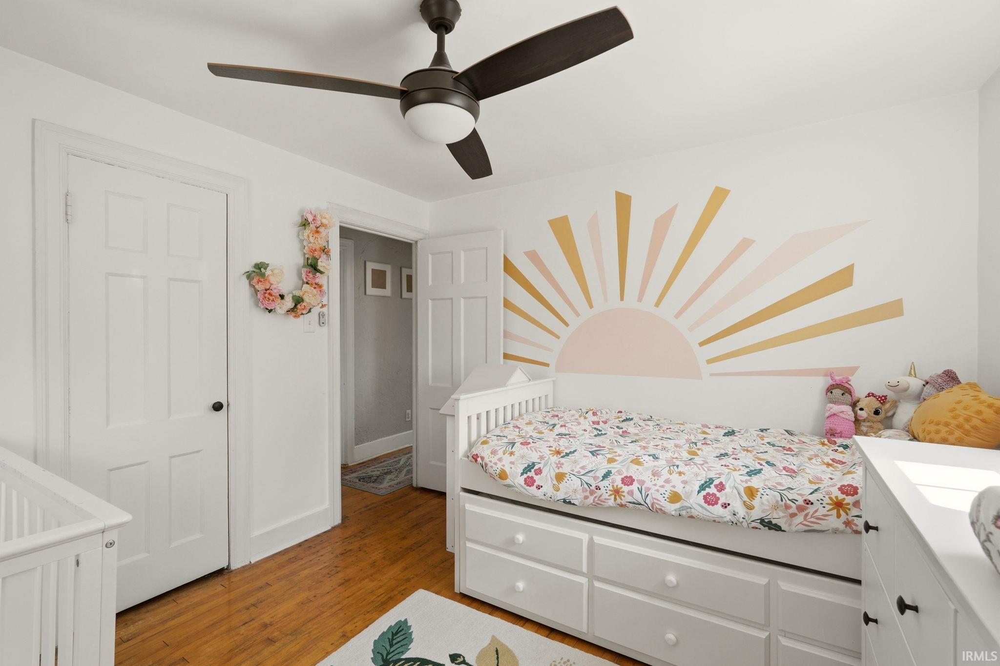 Room featuring wood-finish flooring, a ceiling fan with integrated lighting, and white paneled doors