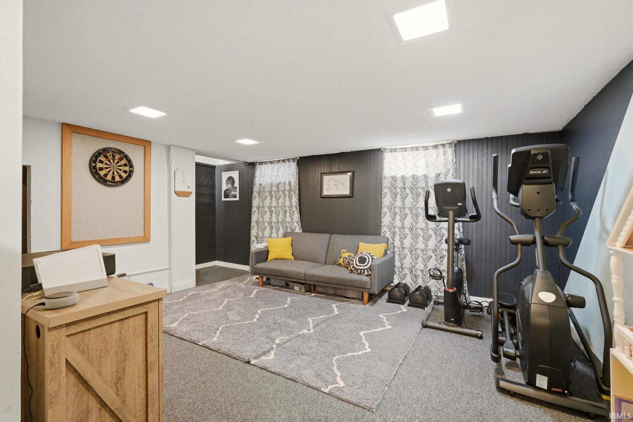 Finished basement space featuring recessed lighting, carpet flooring, dark accent walls, and a built-in dartboard surround