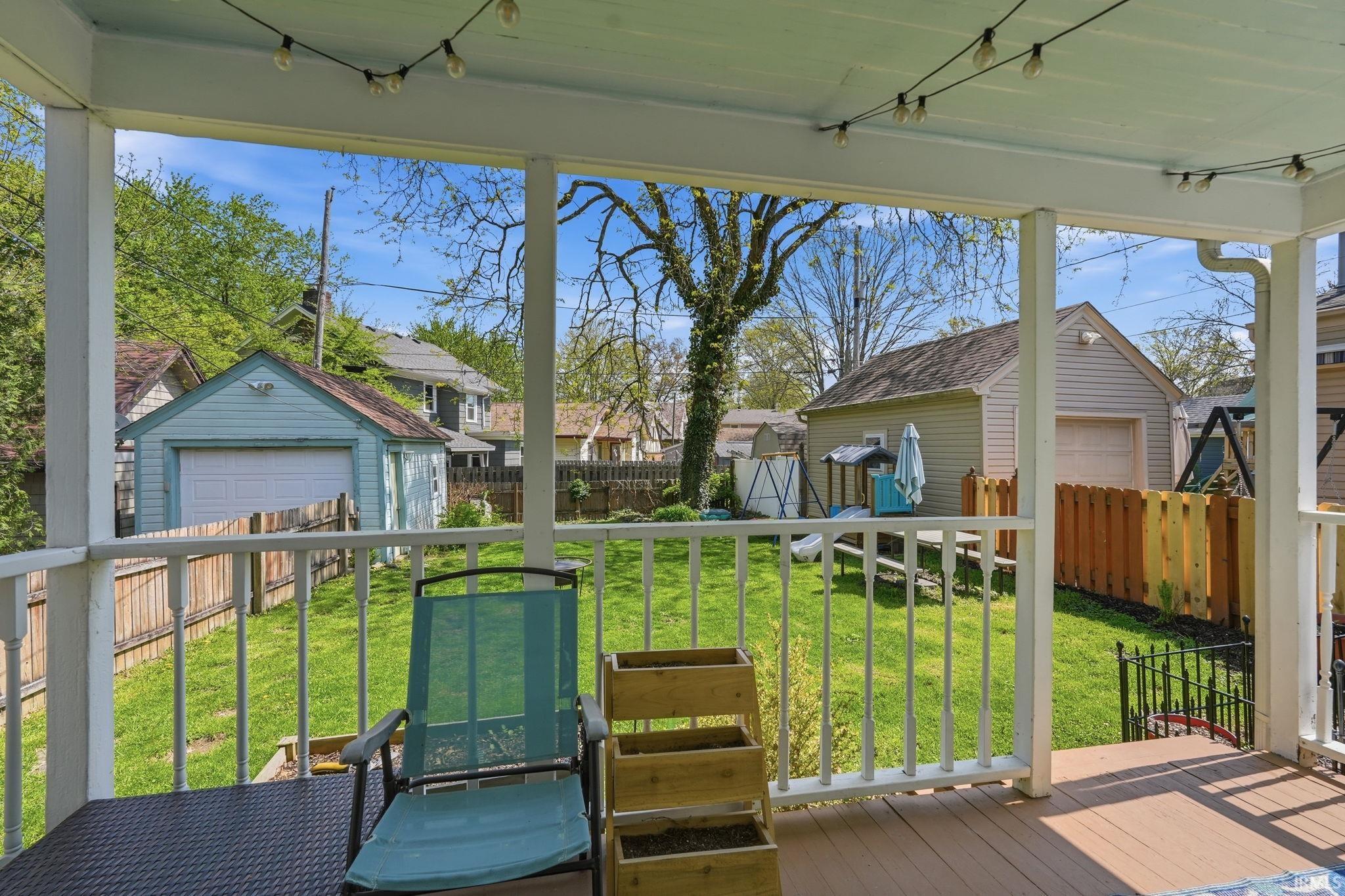 Covered porch with wood-finish flooring and white railings overlooking a fenced backyard