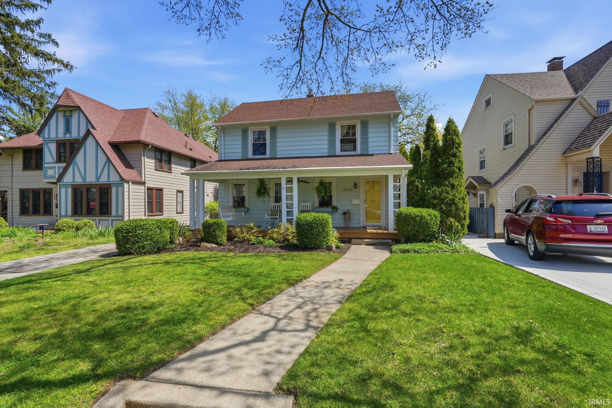 Two-story residence featuring a covered front porch, light blue siding, and a contrasting yellow entry door