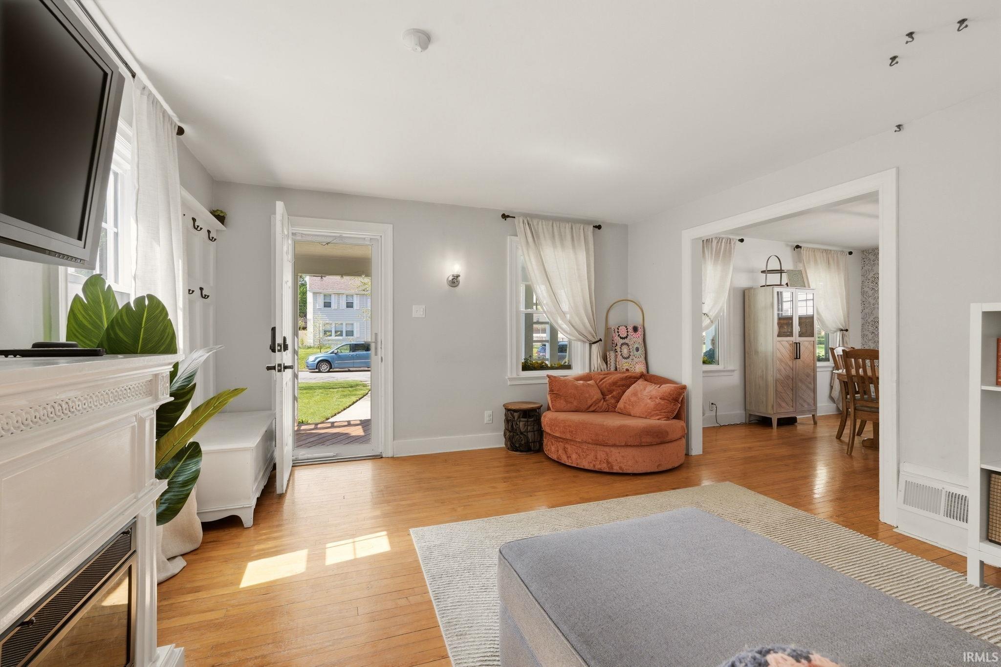 Living area featuring wood-finish flooring and a white fireplace surround