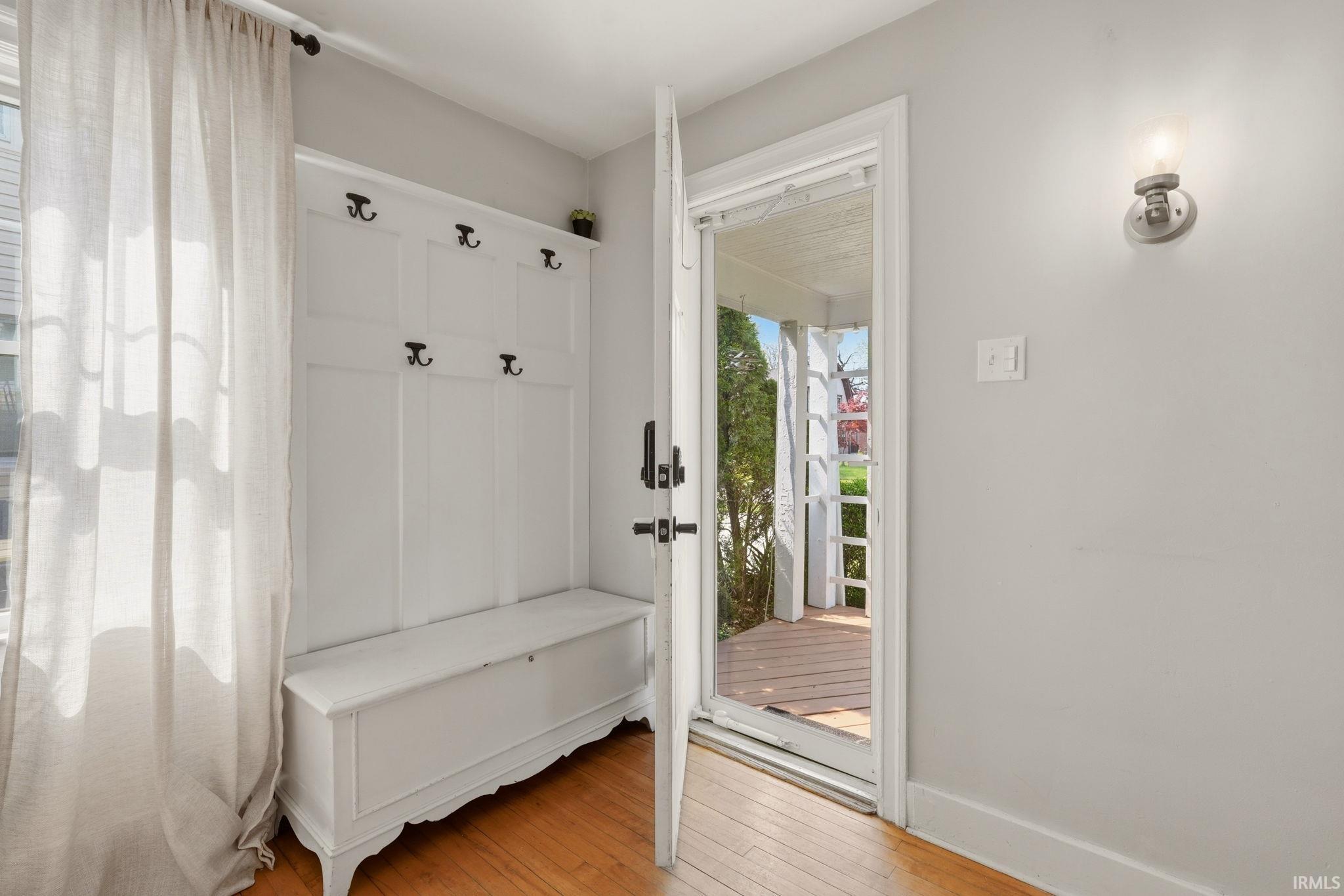 Entryway featuring hardwood flooring, a built-in white hall tree with bench storage, and a transom window above the door
