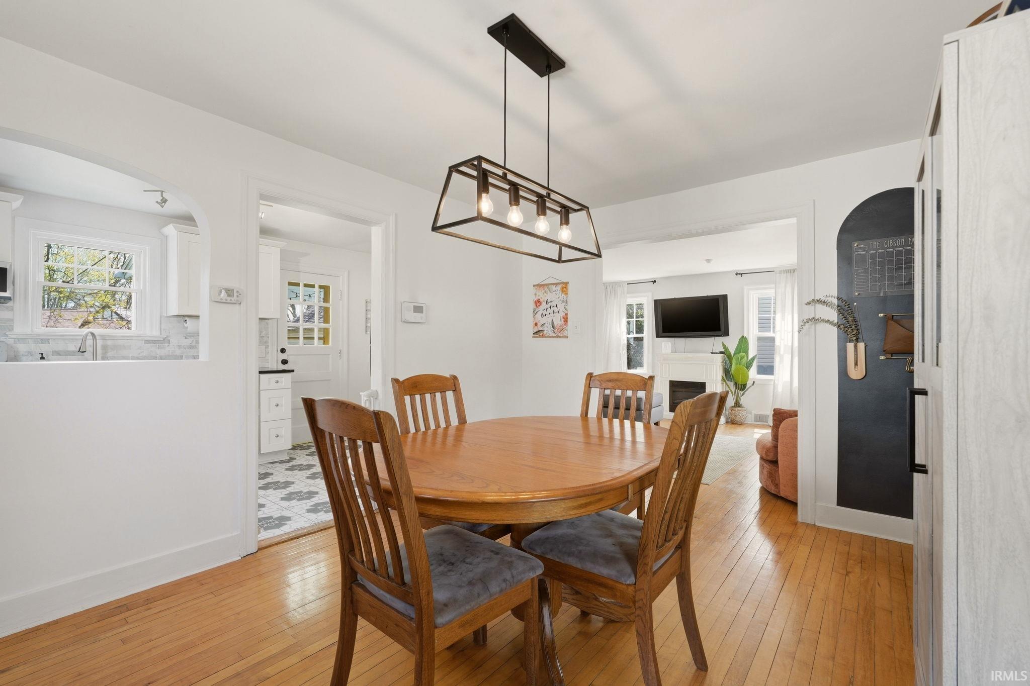 Hardwood flooring extends throughout this dining area, featuring a linear metal chandelier with exposed bulbs