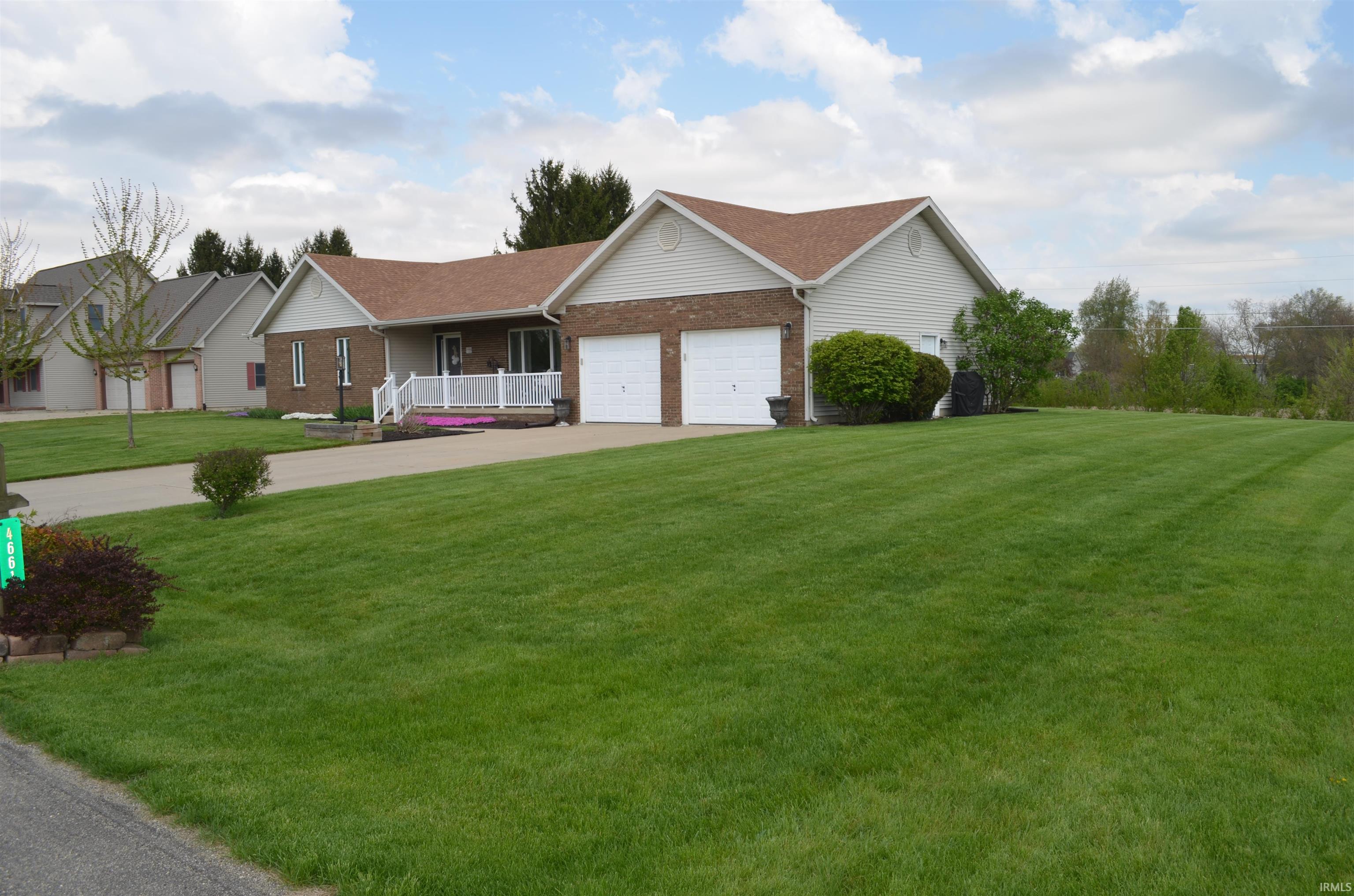 Ranch-style residence featuring a brick facade, white siding, and a two-car attached garage