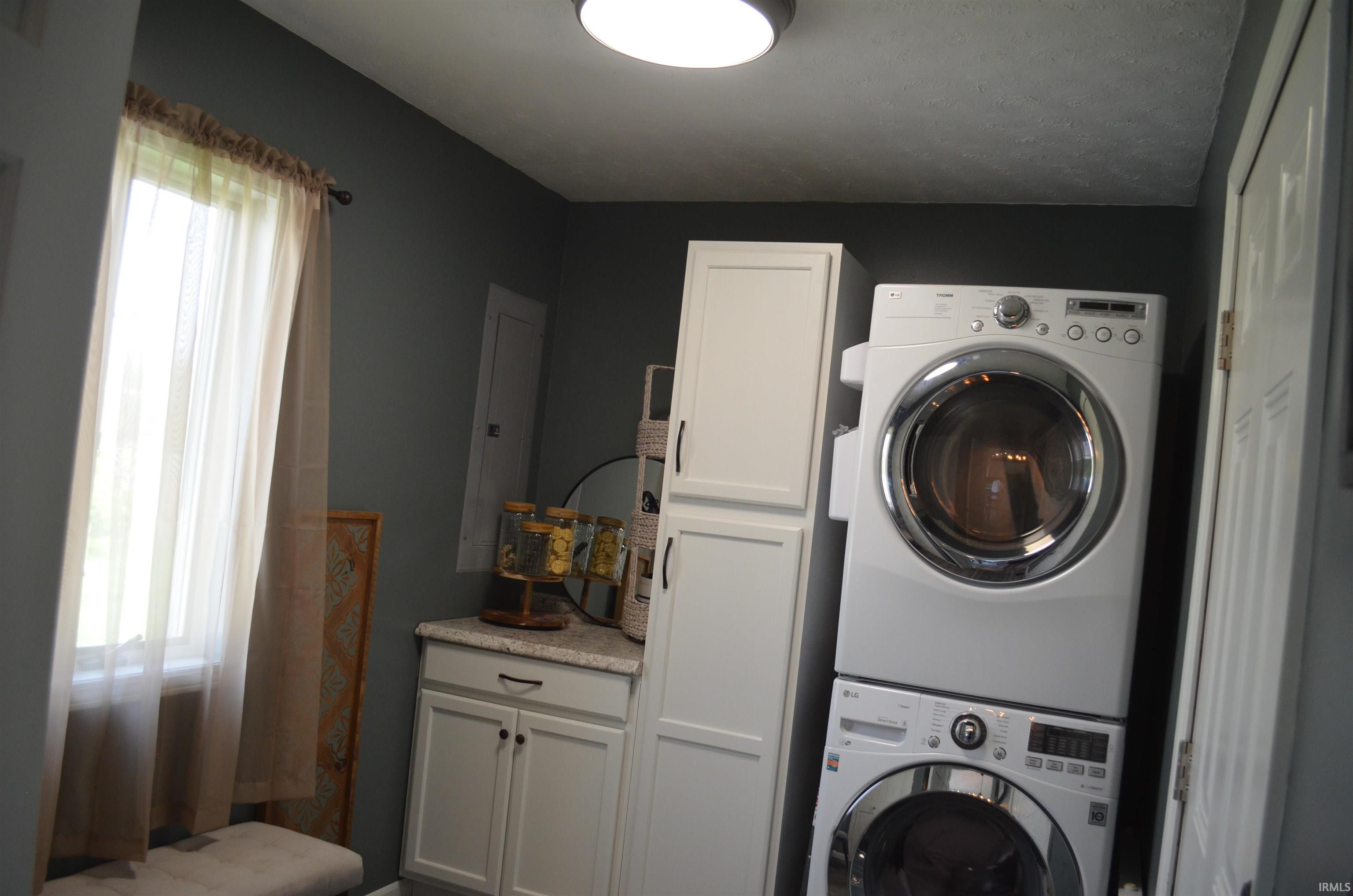 Laundry area featuring a large window, built-in white cabinetry, a countertop, and dark gray walls