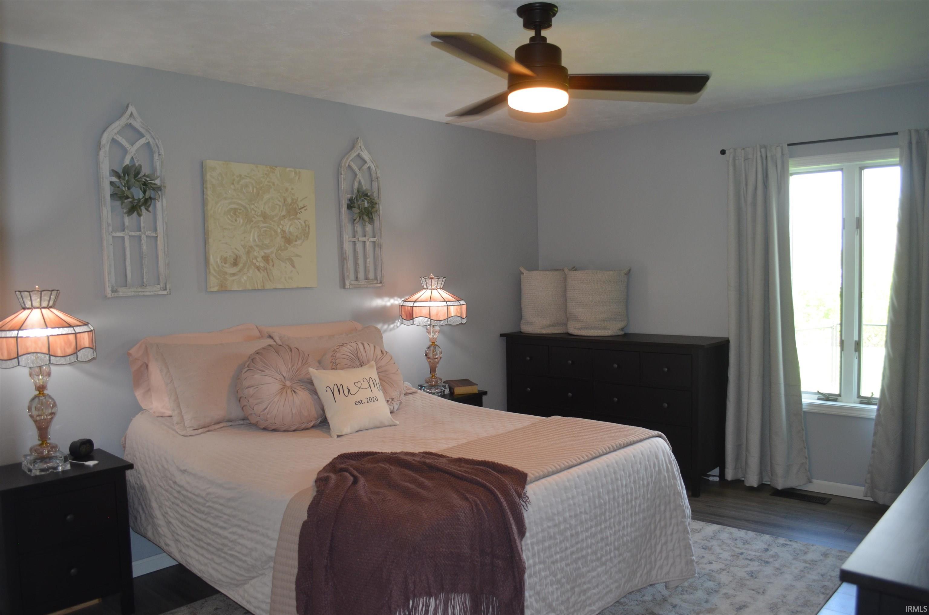 Interior room featuring a ceiling fan with integrated lighting, a window with natural light, and wood-finish flooring