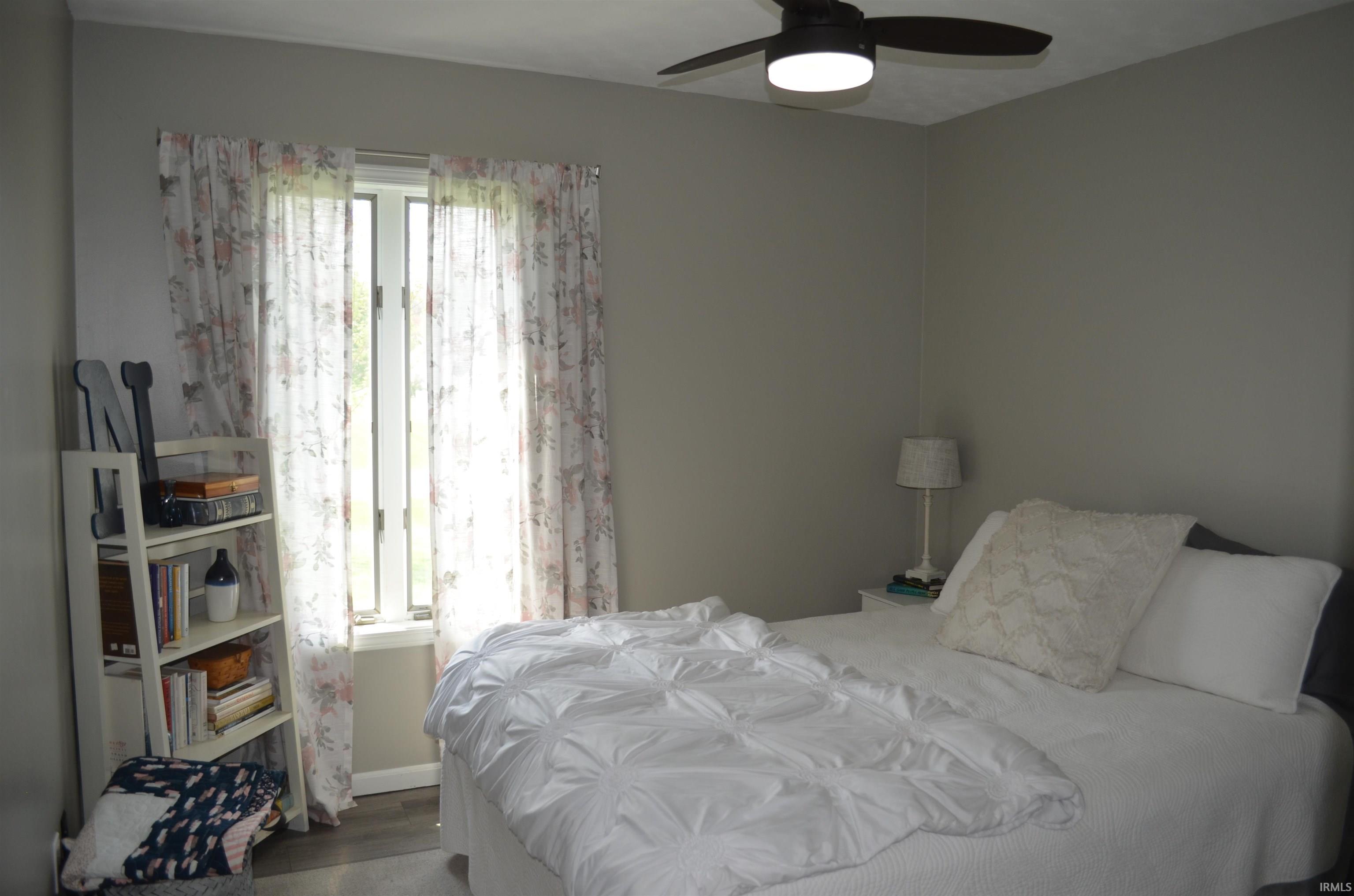 Interior space with neutral wall color, overhead ceiling fan with lighting, and wood-finish flooring