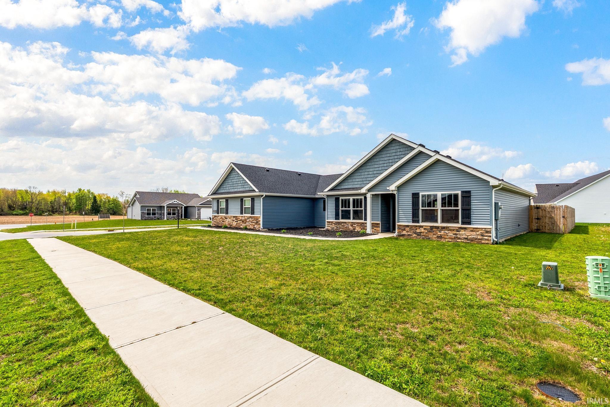 Contemporary ranch-style home featuring blue siding, a stone facade, and dark window shutters