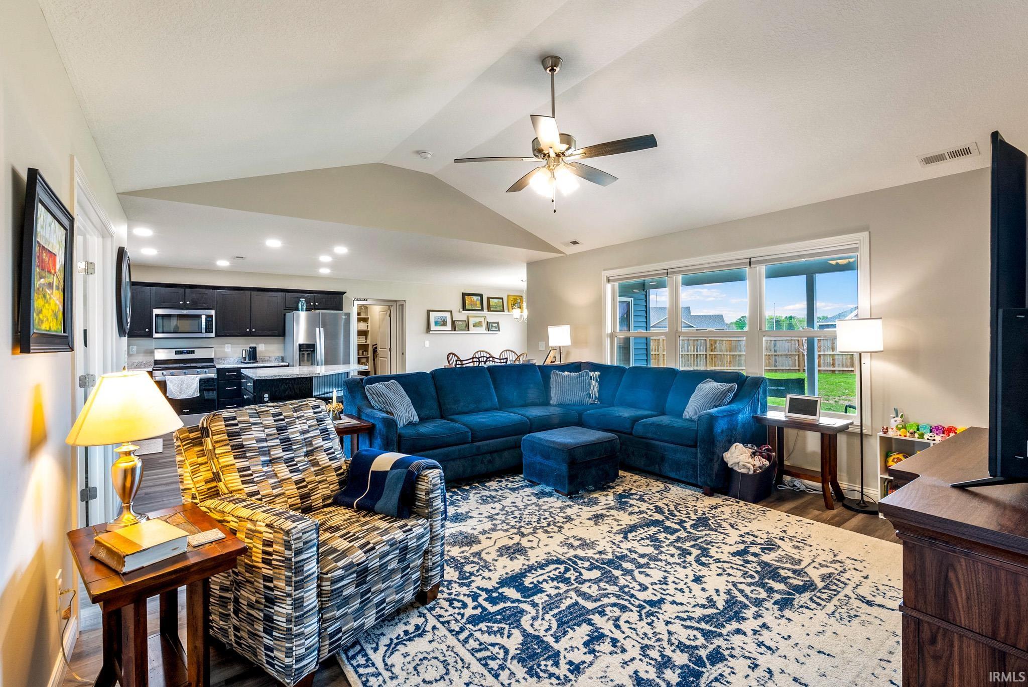 Open-concept living space featuring vaulted ceilings, recessed lighting, and wood-finish flooring