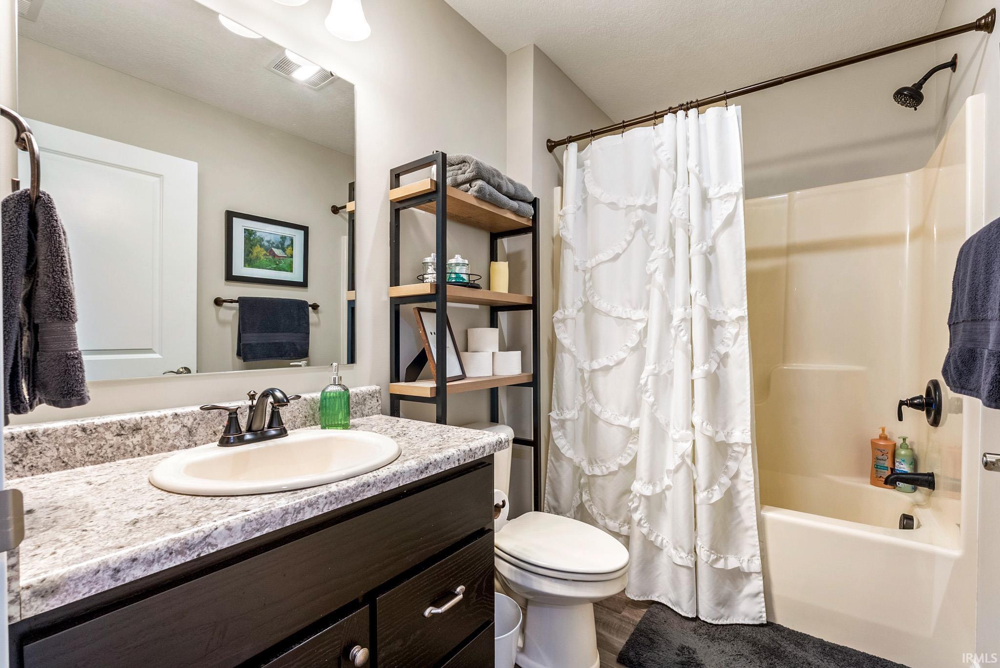 Bathroom featuring a vanity with a light-toned countertop, integrated sink, and dark cabinetry
