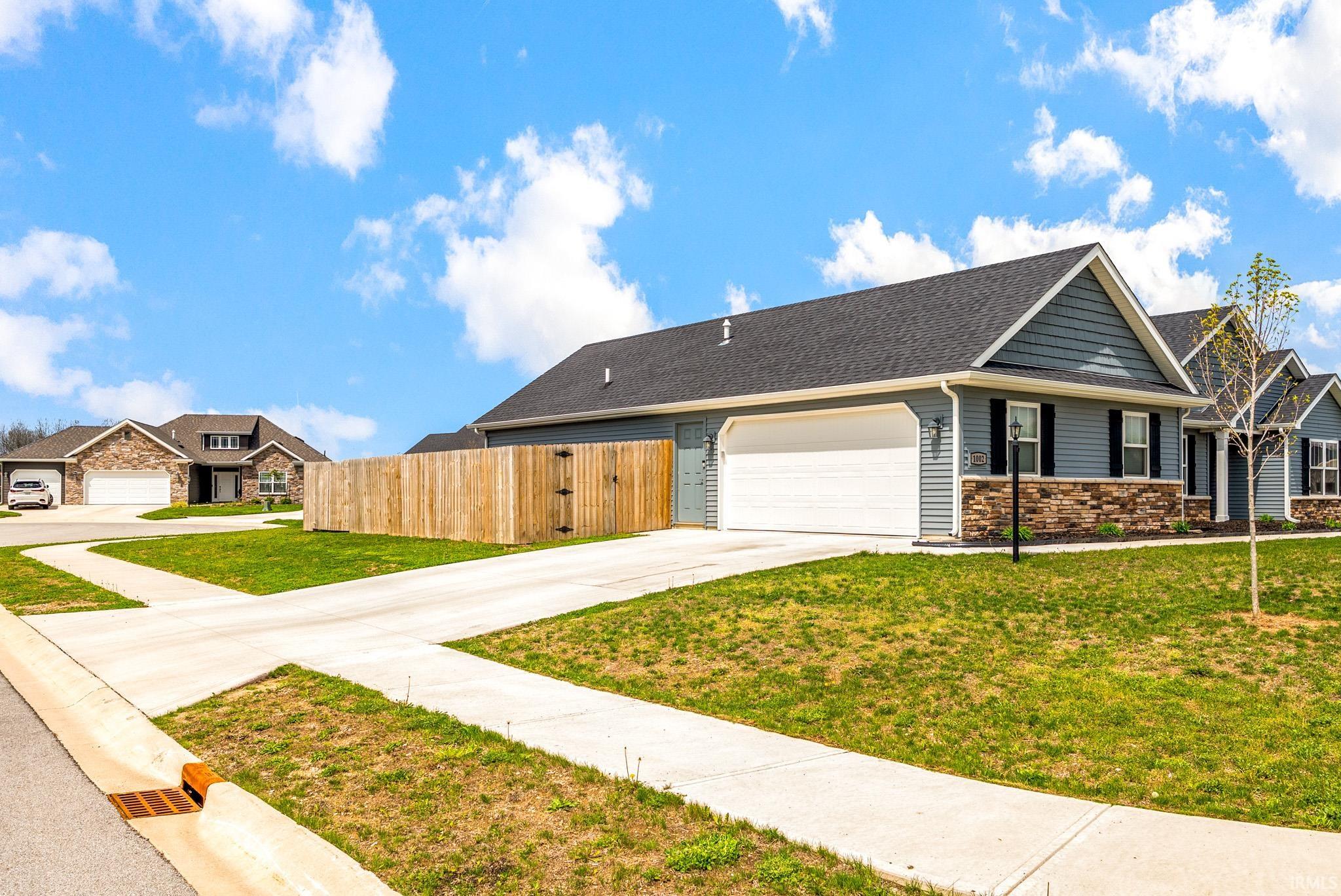 Ranch-style exterior with gray siding, stone accents, and a dark shingle roof