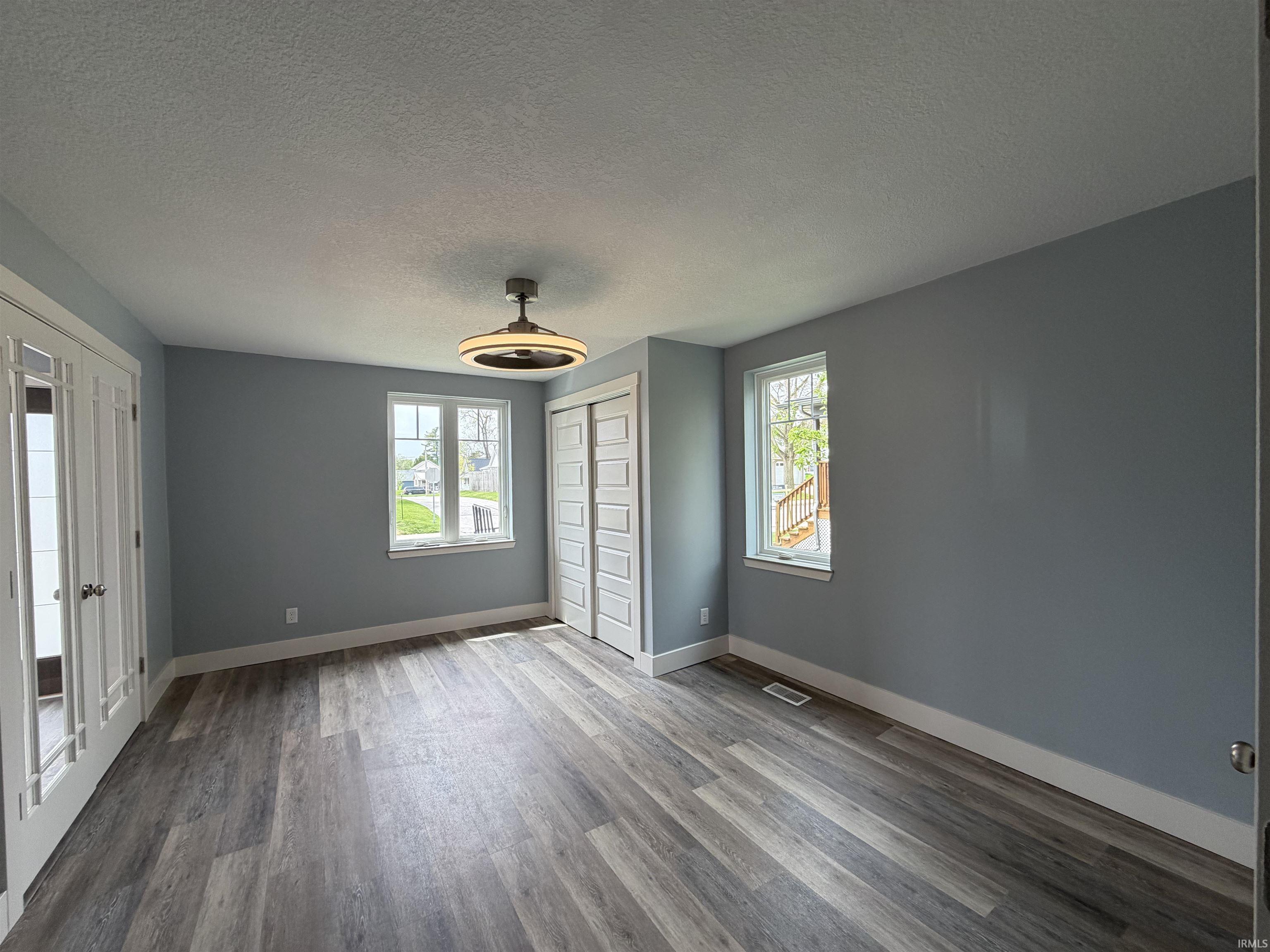 Unfurnished bedroom with a textured ceiling, light wood finished floors, a closet, and ceiling fan