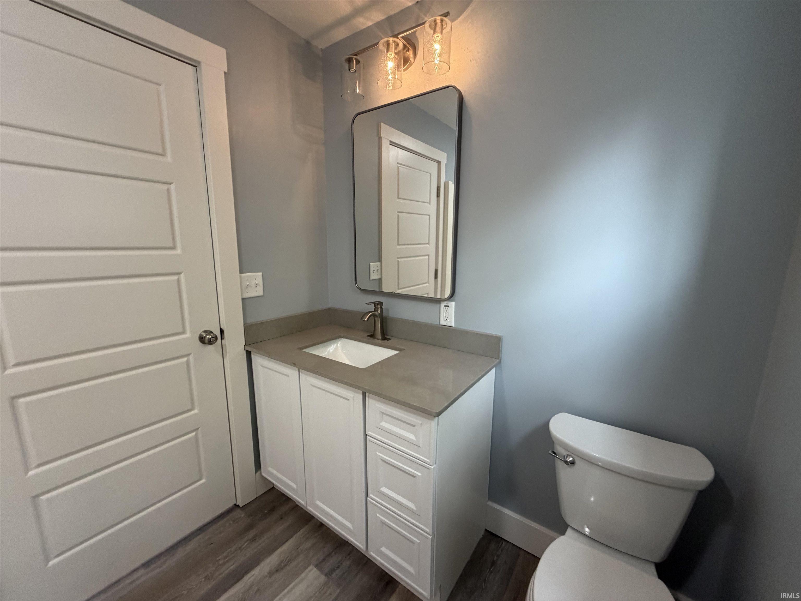 Half bath featuring vanity and dark wood finished floors
