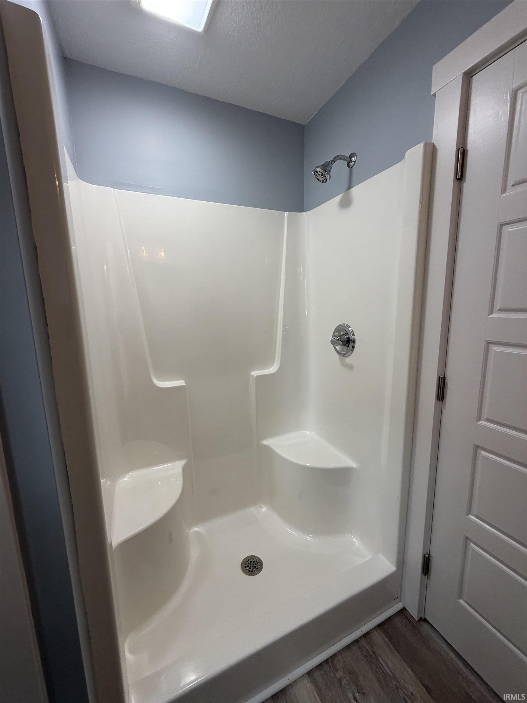 Bathroom featuring a stall shower, dark wood-type flooring, and a textured ceiling