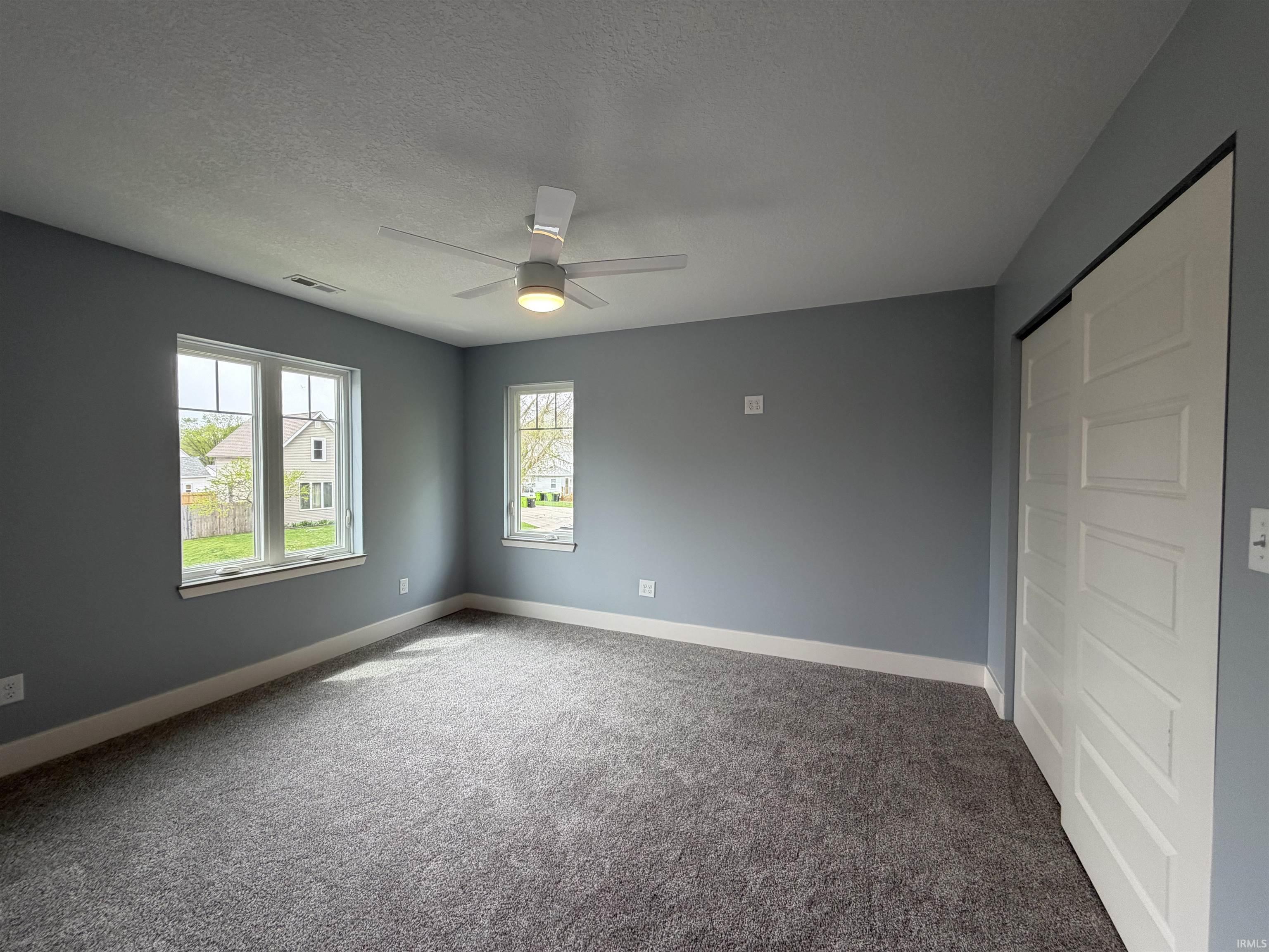 Unfurnished bedroom with light colored carpet, a closet, a ceiling fan, and a textured ceiling