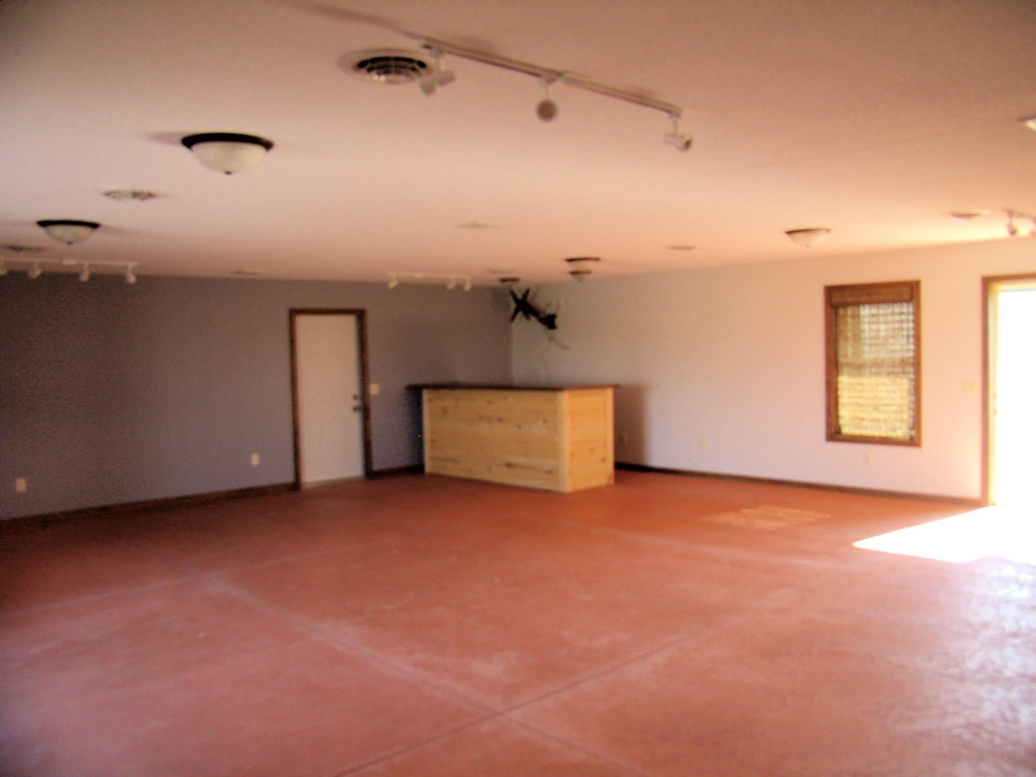 Spacious interior with expansive red-toned flooring, track lighting, and flush-mount ceiling fixtures