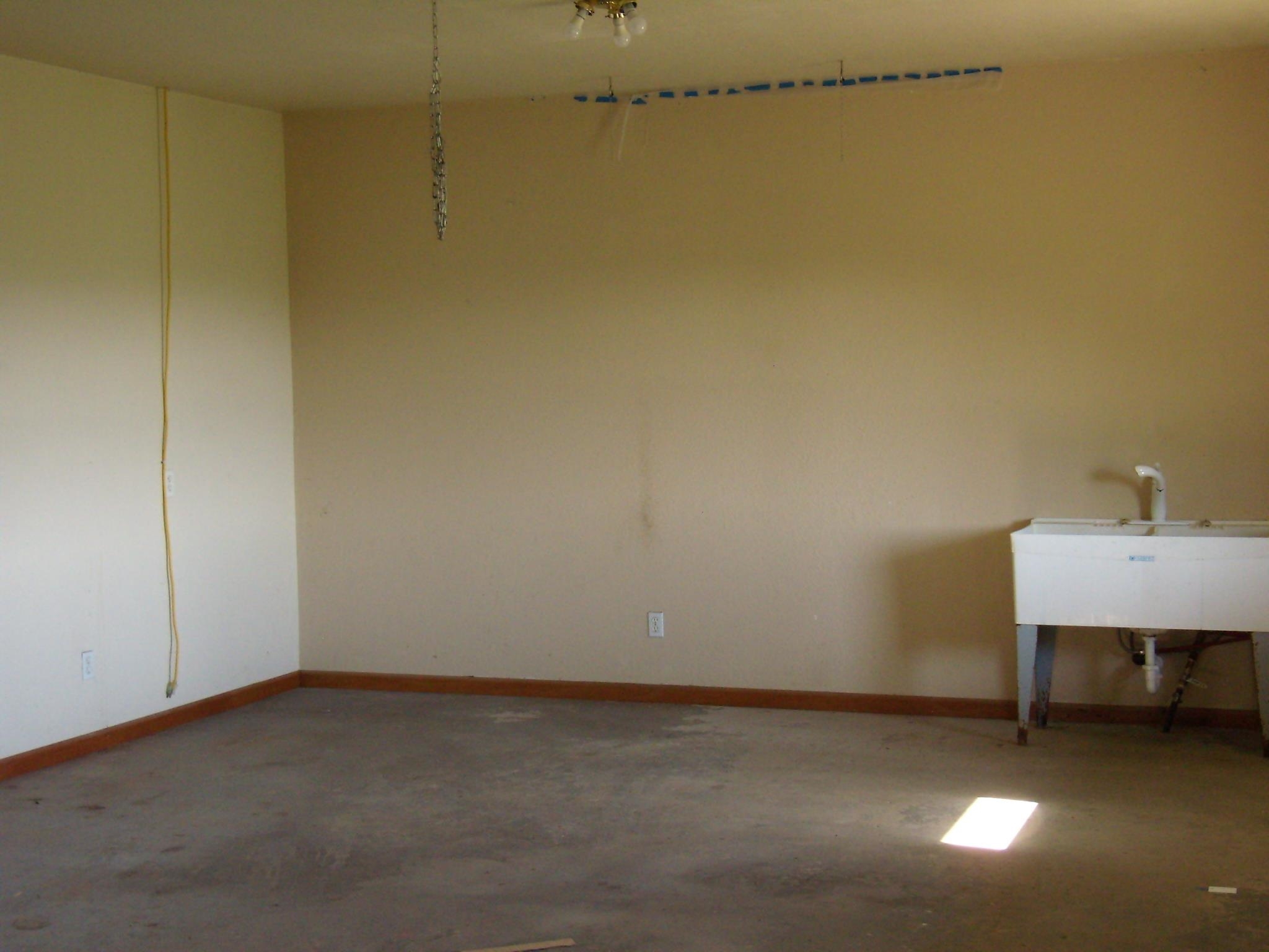 Spacious utility room featuring a built-in double basin sink, neutral wall tones, and durable concrete flooring