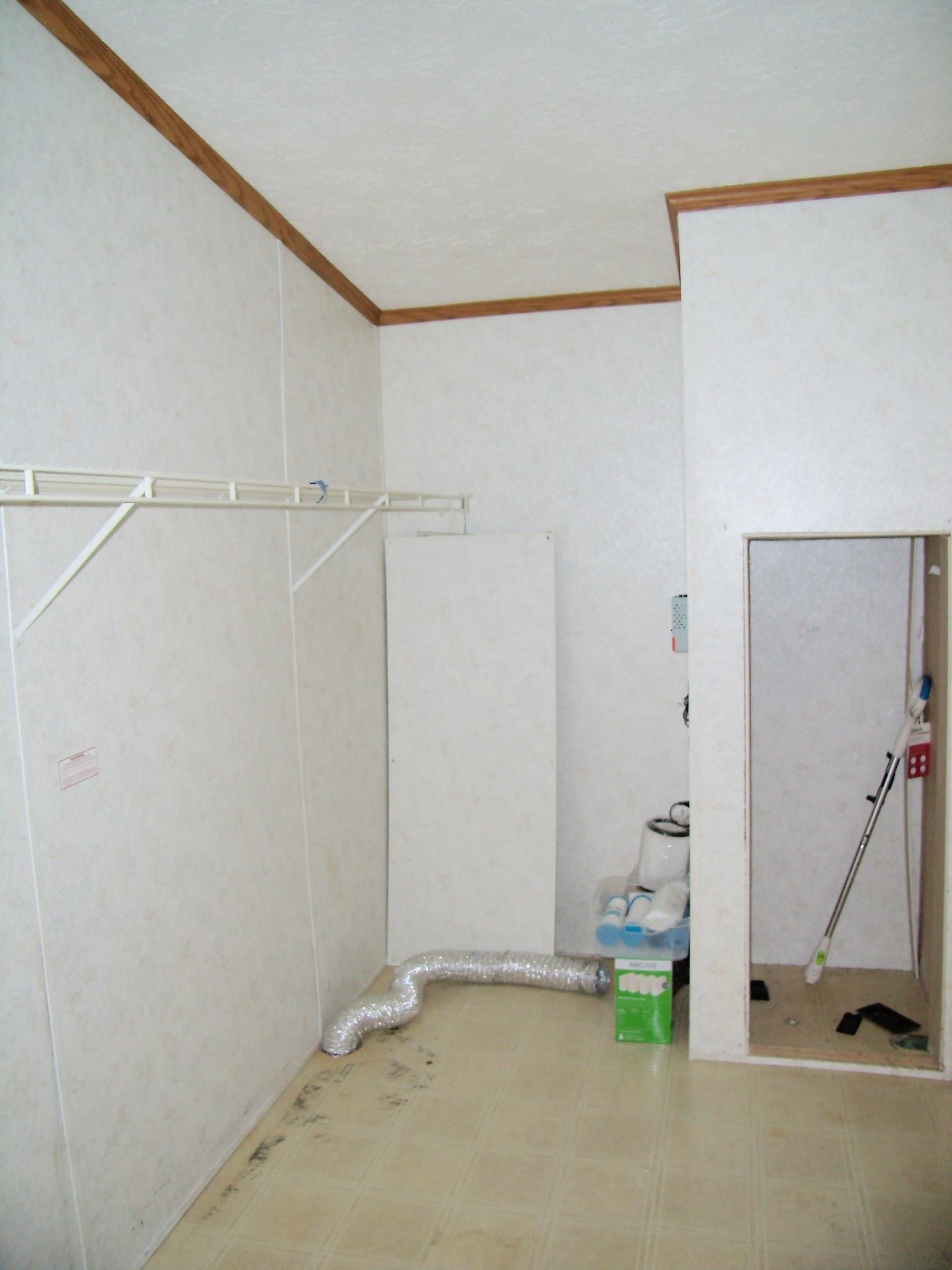 Utility space featuring light-colored panel walls, crown molding, and resilient flooring
