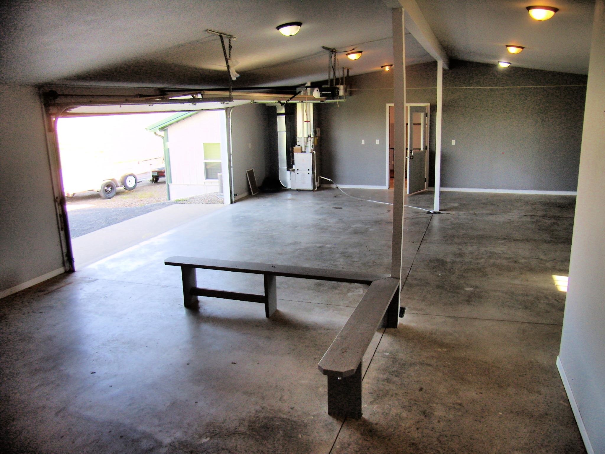 Spacious garage featuring a concrete floor, multiple flush-mount light fixtures, an automatic overhead door, and painted gray walls