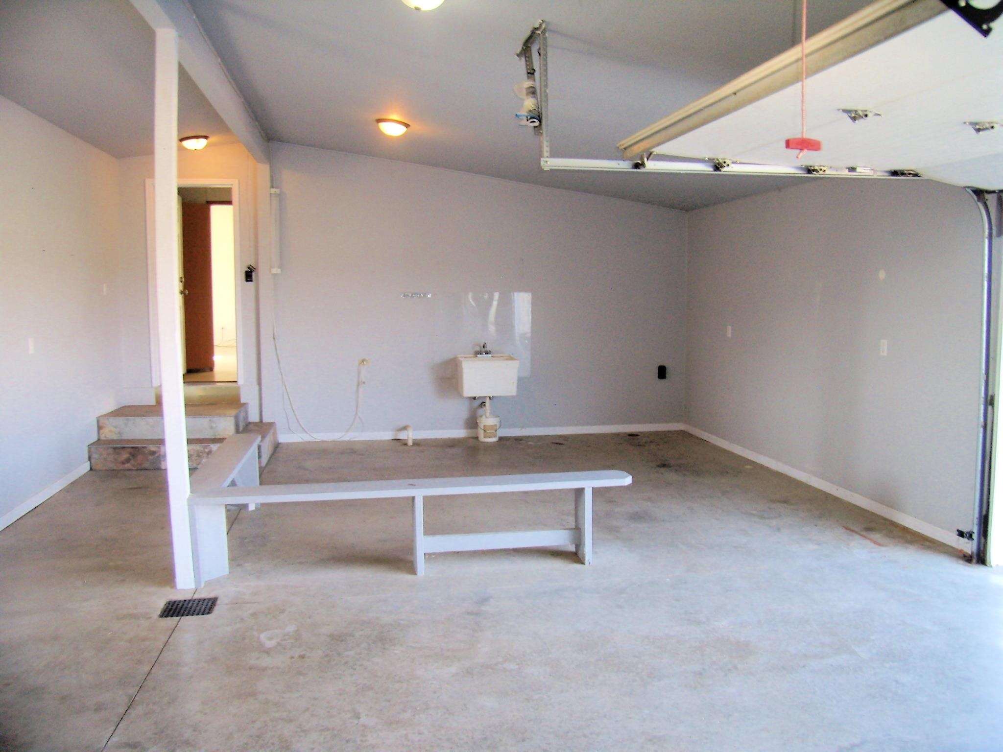 Spacious garage with concrete flooring, sloped ceiling, and overhead lighting